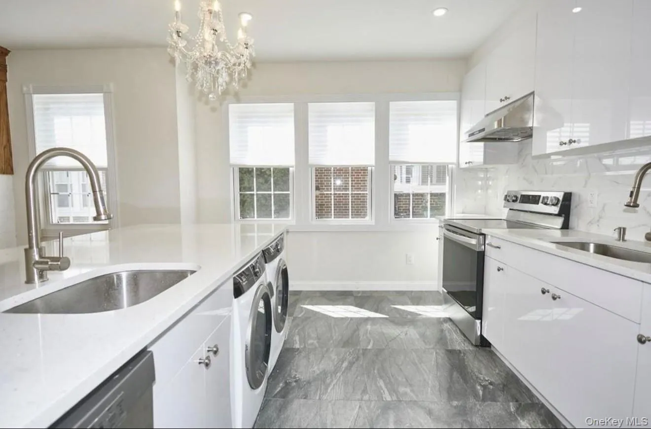 Kitchen with stainless steel appliances, white cabinets, light stone countertops, under cabinet range hood, and healthy amount of natural light Kitchen with stainless steel appliances, white cabinets, light stone countertops, under cabinet range hood, and healthy amount of natural light