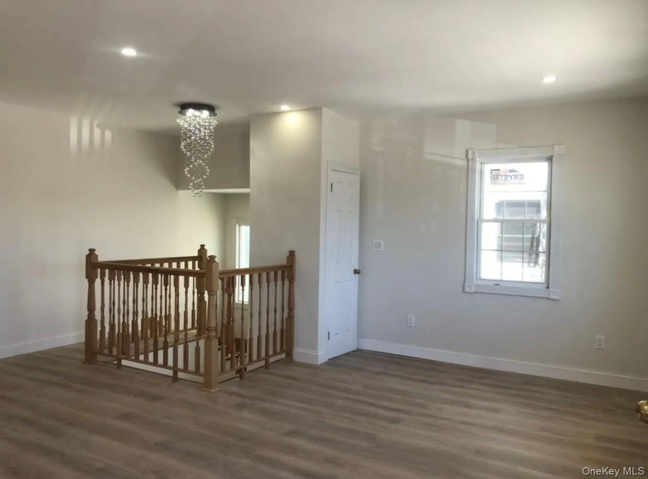 Empty room featuring dark wood-style flooring, recessed lighting, and a chandelier Empty room featuring dark wood-style flooring, recessed lighting, and a chandelier