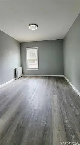 Unfurnished room with wood finished floors and radiator heating unit Unfurnished room with wood finished floors and radiator heating unit