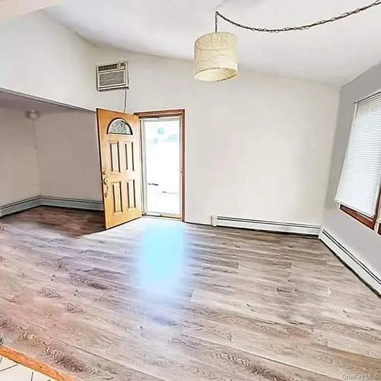 Unfurnished dining area with lofted ceiling, light wood finished floors, plenty of natural light, and a baseboard radiator Unfurnished dining area with lofted ceiling, light wood finished floors, plenty of natural light, and a baseboard radiator