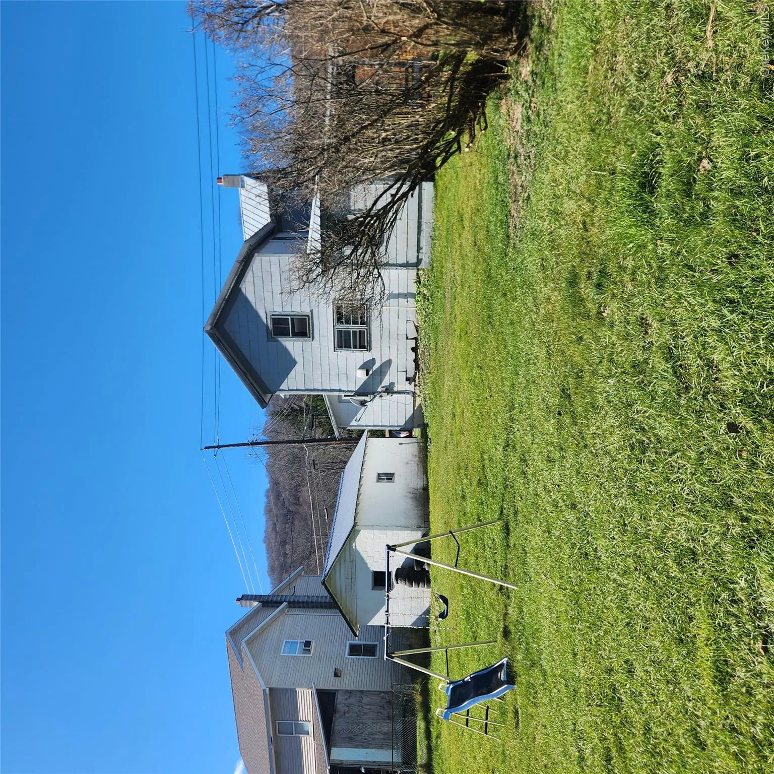 Back of property featuring a metal roof, a chimney, a lawn, and a playground Back of property featuring a metal roof, a chimney, a lawn, and a playground
