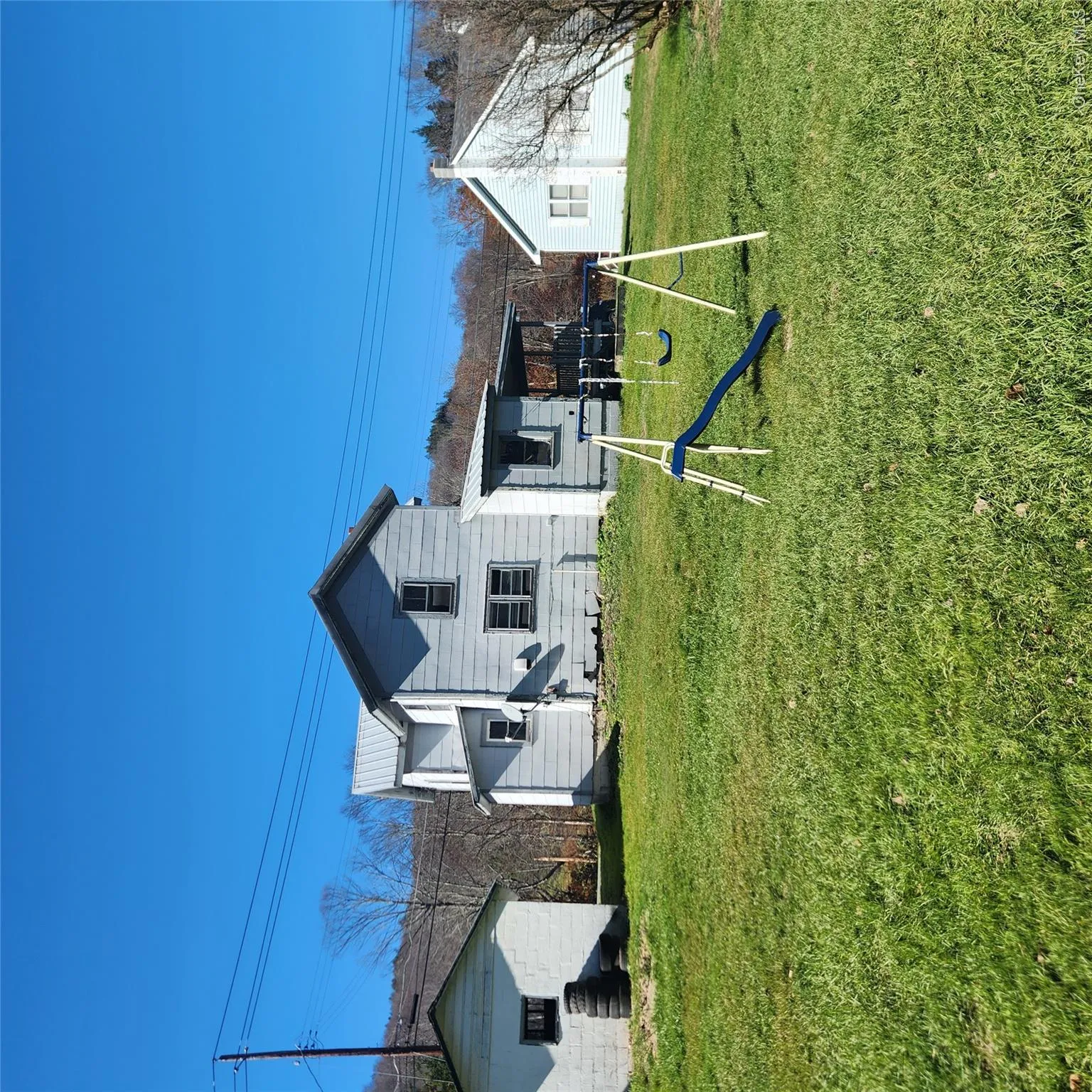Back of house featuring a metal roof, a yard, and a playground Back of house featuring a metal roof, a yard, and a playground