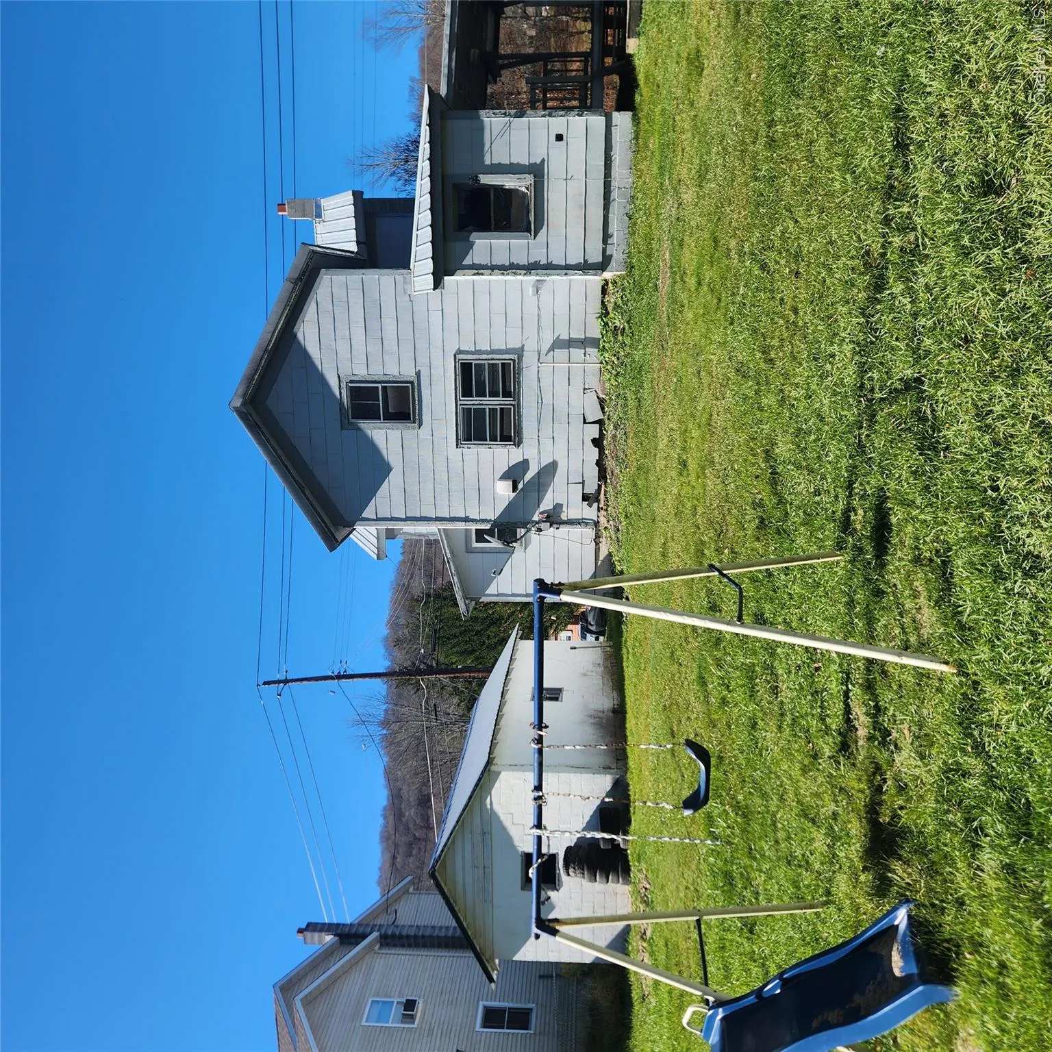 Back of property featuring a playground, a metal roof, a chimney, and a lawn Back of property featuring a playground, a metal roof, a chimney, and a lawn