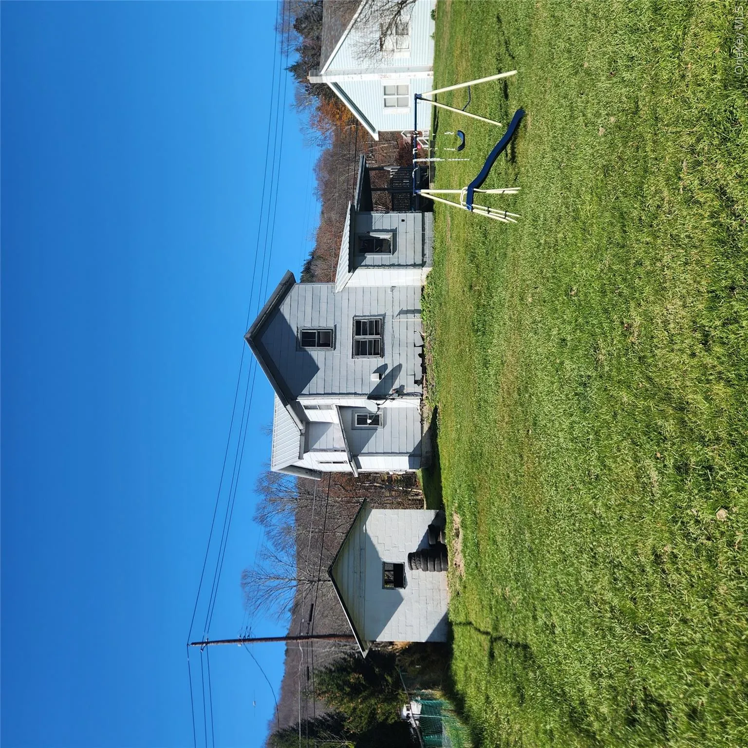 Rear view of house featuring a lawn, an outdoor structure, and a metal roof Rear view of house featuring a lawn, an outdoor structure, and a metal roof