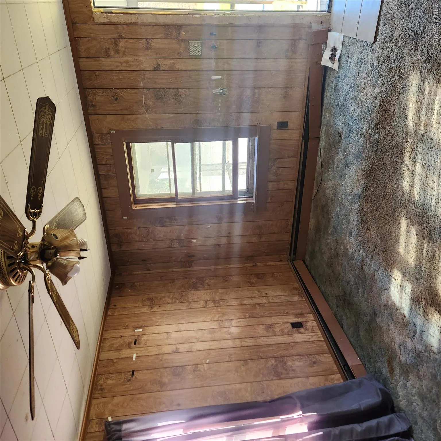 Empty room with wooden walls, dark colored carpet, and ceiling fan Empty room with wooden walls, dark colored carpet, and ceiling fan