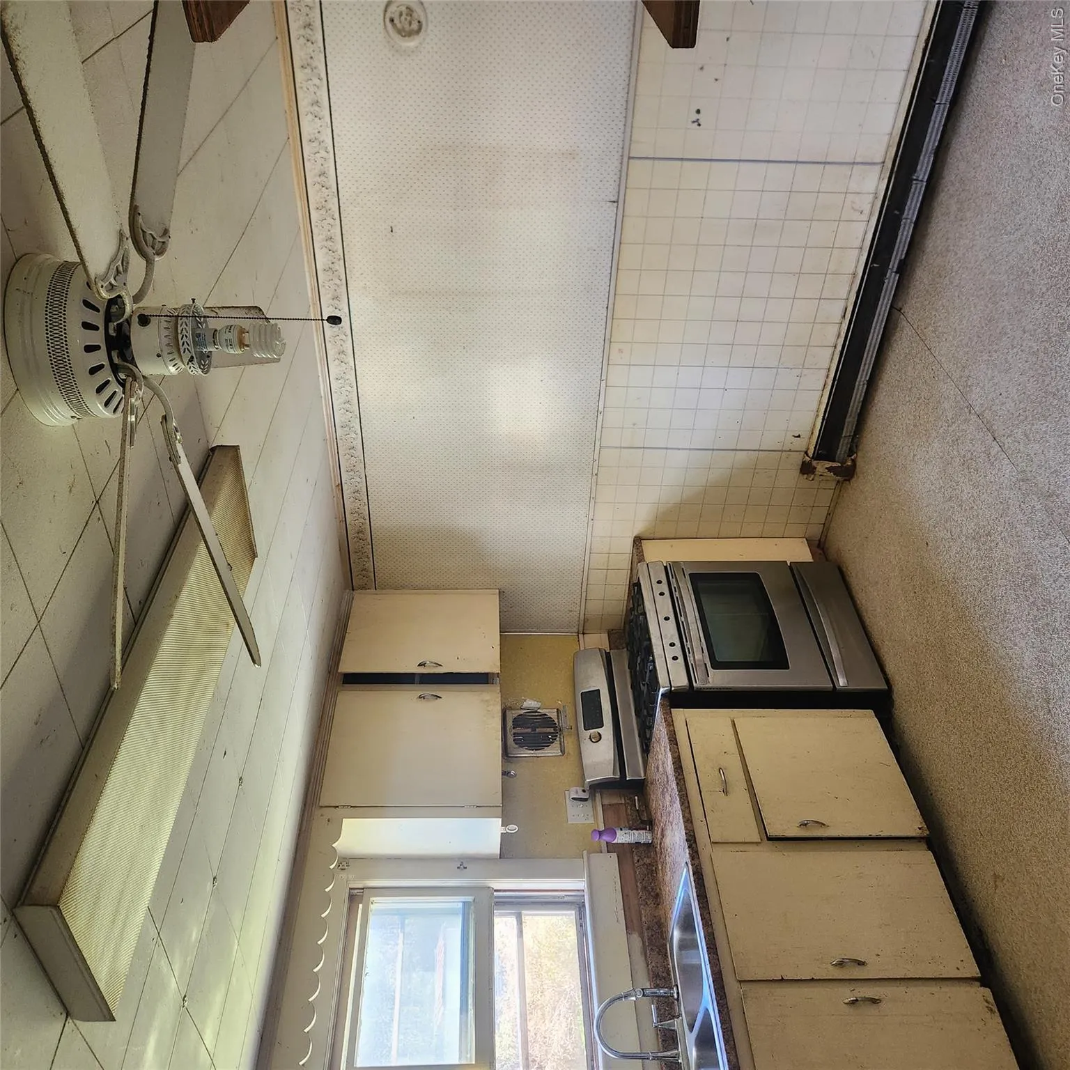 Kitchen with a wainscoted wall, tile walls, range, dark countertops, and wallpapered walls Kitchen with a wainscoted wall, tile walls, range, dark countertops, and wallpapered walls