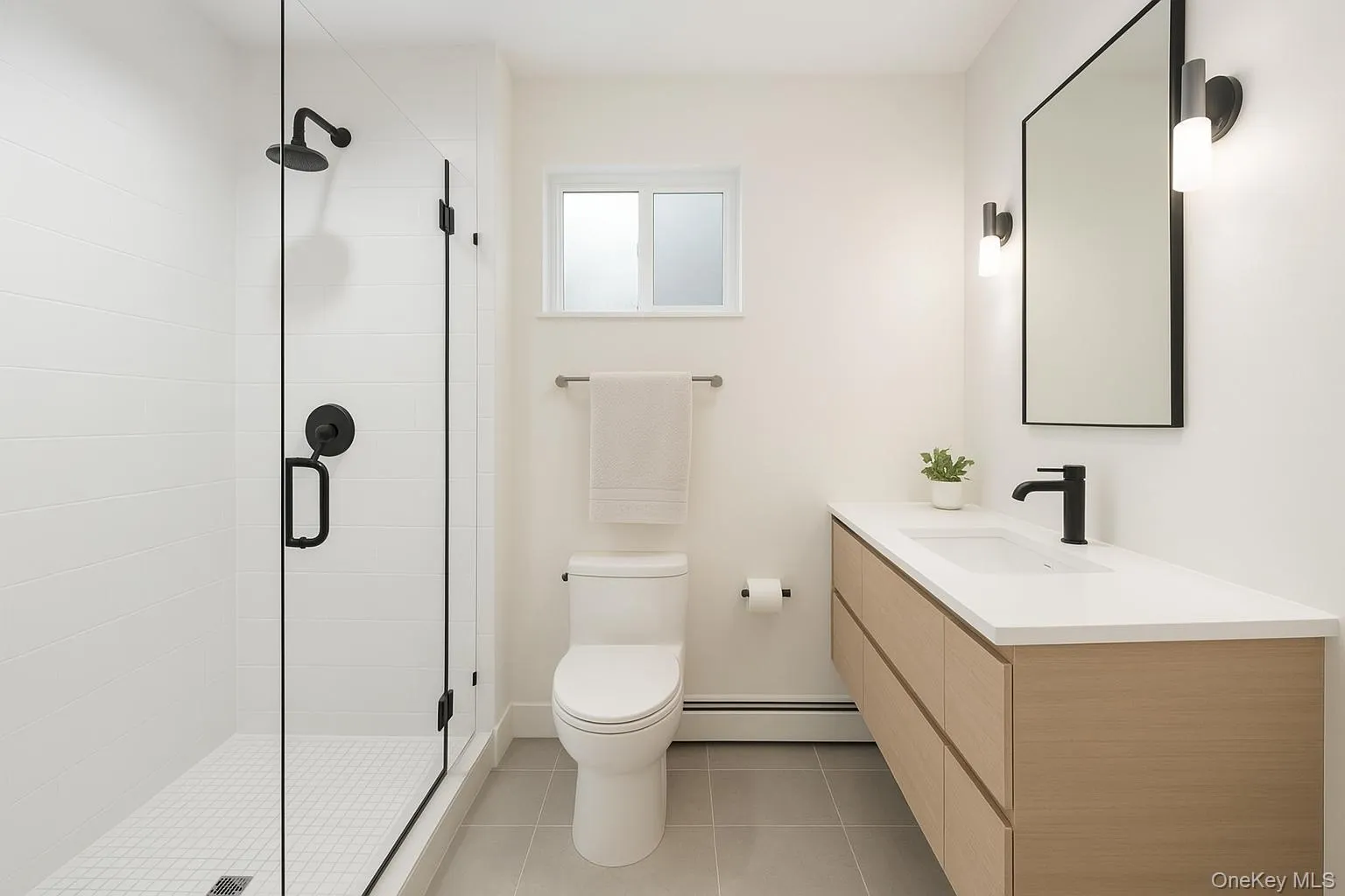 Full bathroom with vanity, a baseboard heating unit, a stall shower, and light tile patterned floors Full bathroom with vanity, a baseboard heating unit, a stall shower, and light tile patterned floors