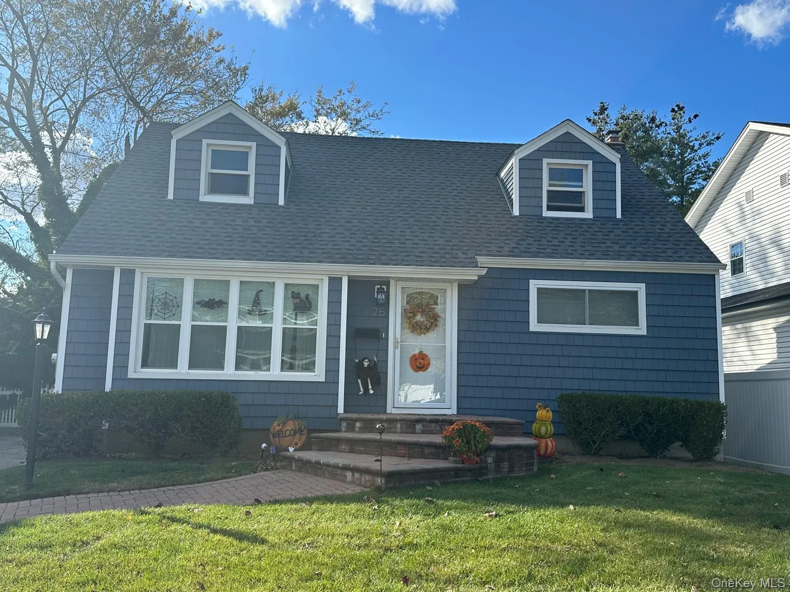 Cape cod house featuring a front yard, a shingled roof, and a chimney Cape cod house featuring a front yard, a shingled roof, and a chimney