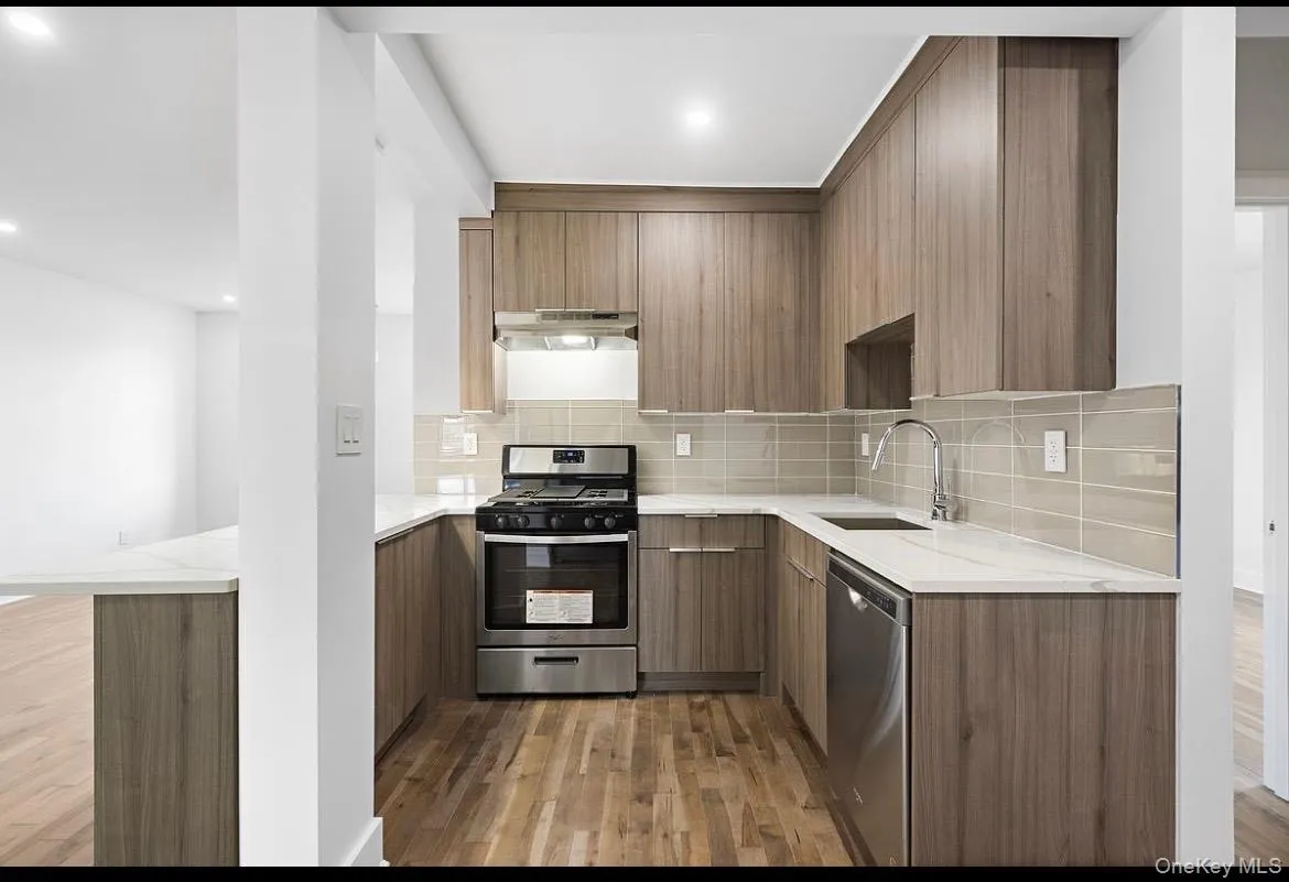 Kitchen with stainless steel appliances, light wood-style flooring, backsplash, light stone countertops, and modern cabinets Kitchen with stainless steel appliances, light wood-style flooring, backsplash, light stone countertops, and modern cabinets