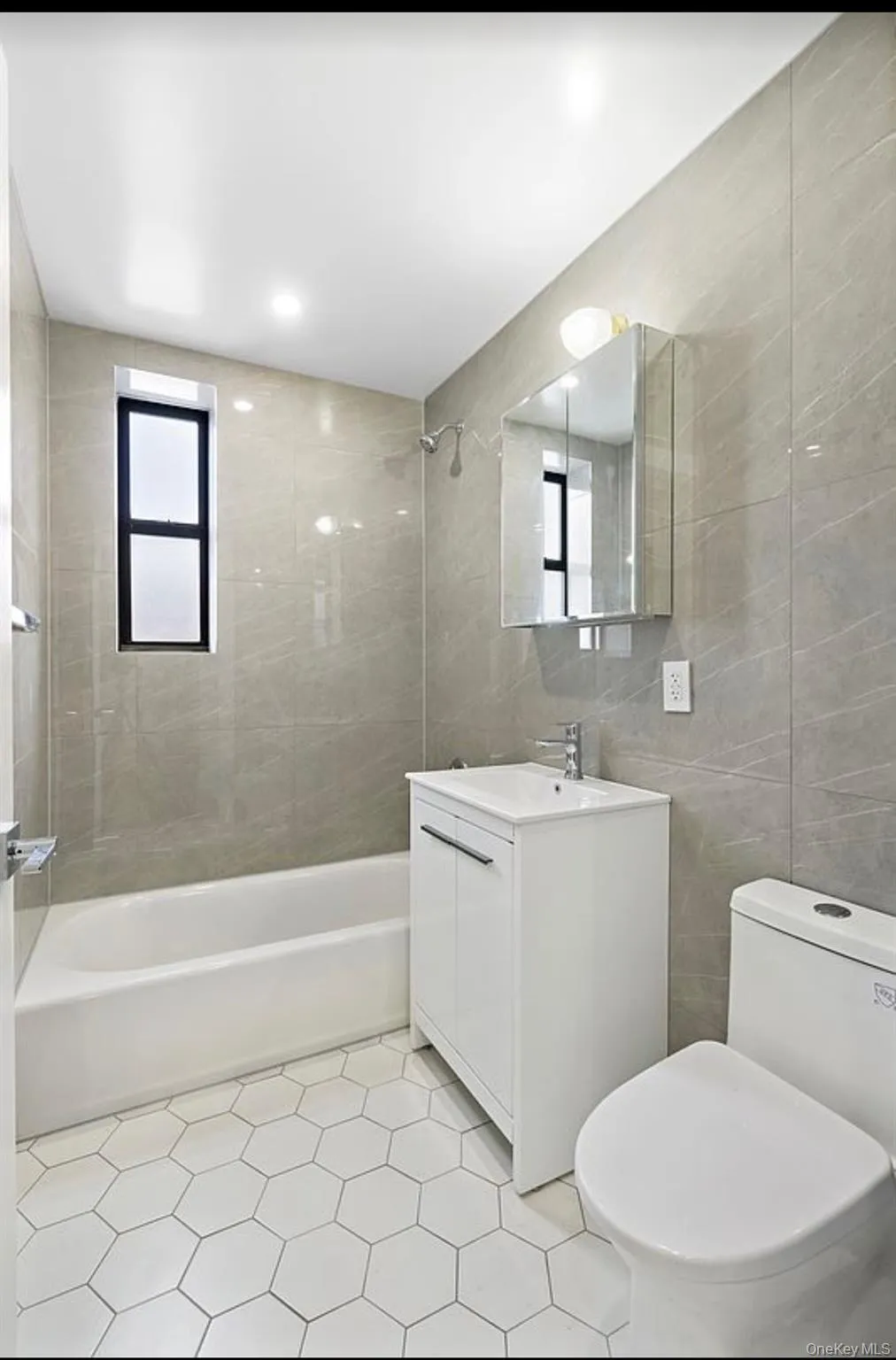 Bathroom with tile walls, bathing tub / shower combination, vanity, healthy amount of natural light, and light tile patterned floors Bathroom with tile walls, bathing tub / shower combination, vanity, healthy amount of natural light, and light tile patterned floors