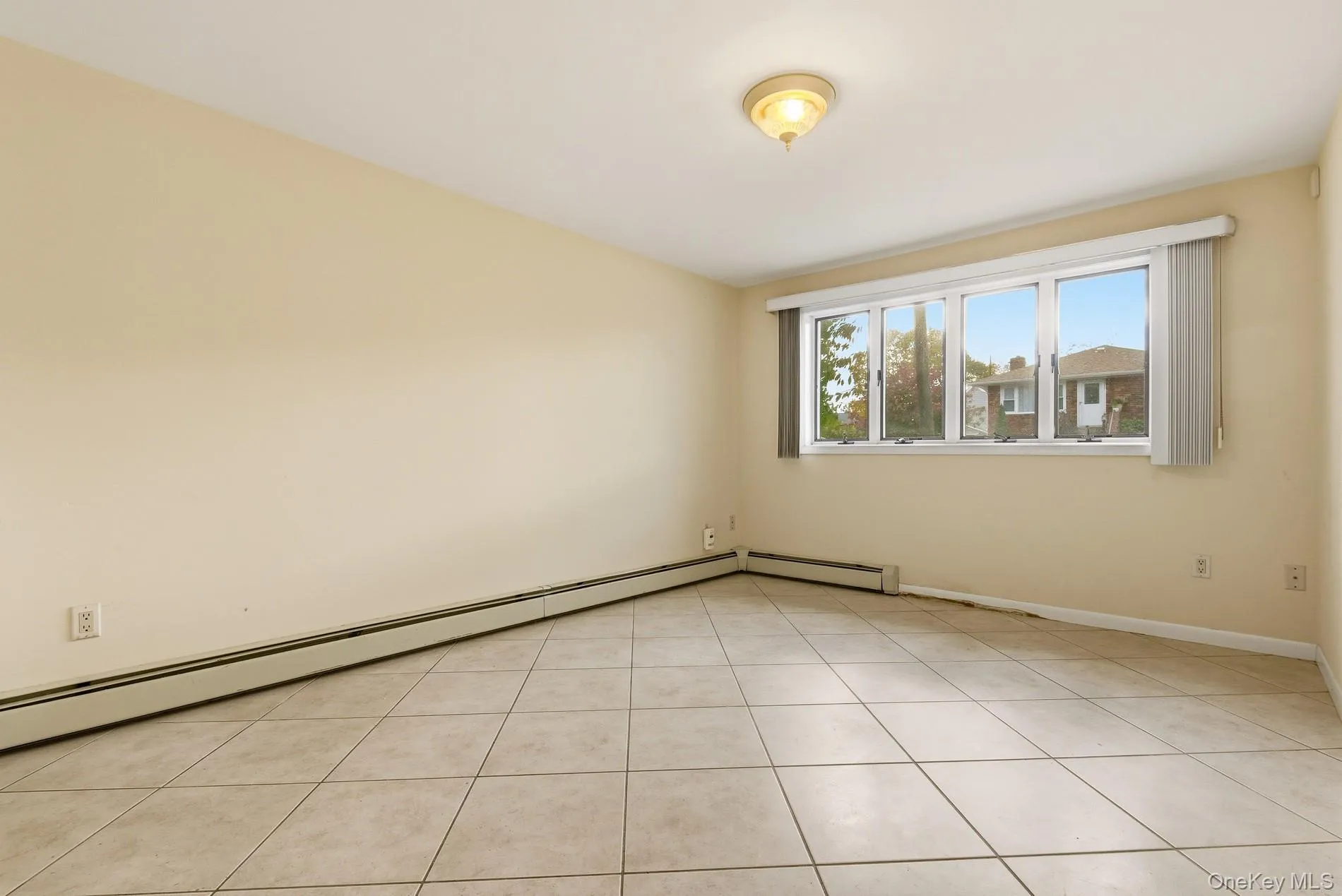 Unfurnished room with baseboard heating and light tile patterned floors Unfurnished room with baseboard heating and light tile patterned floors