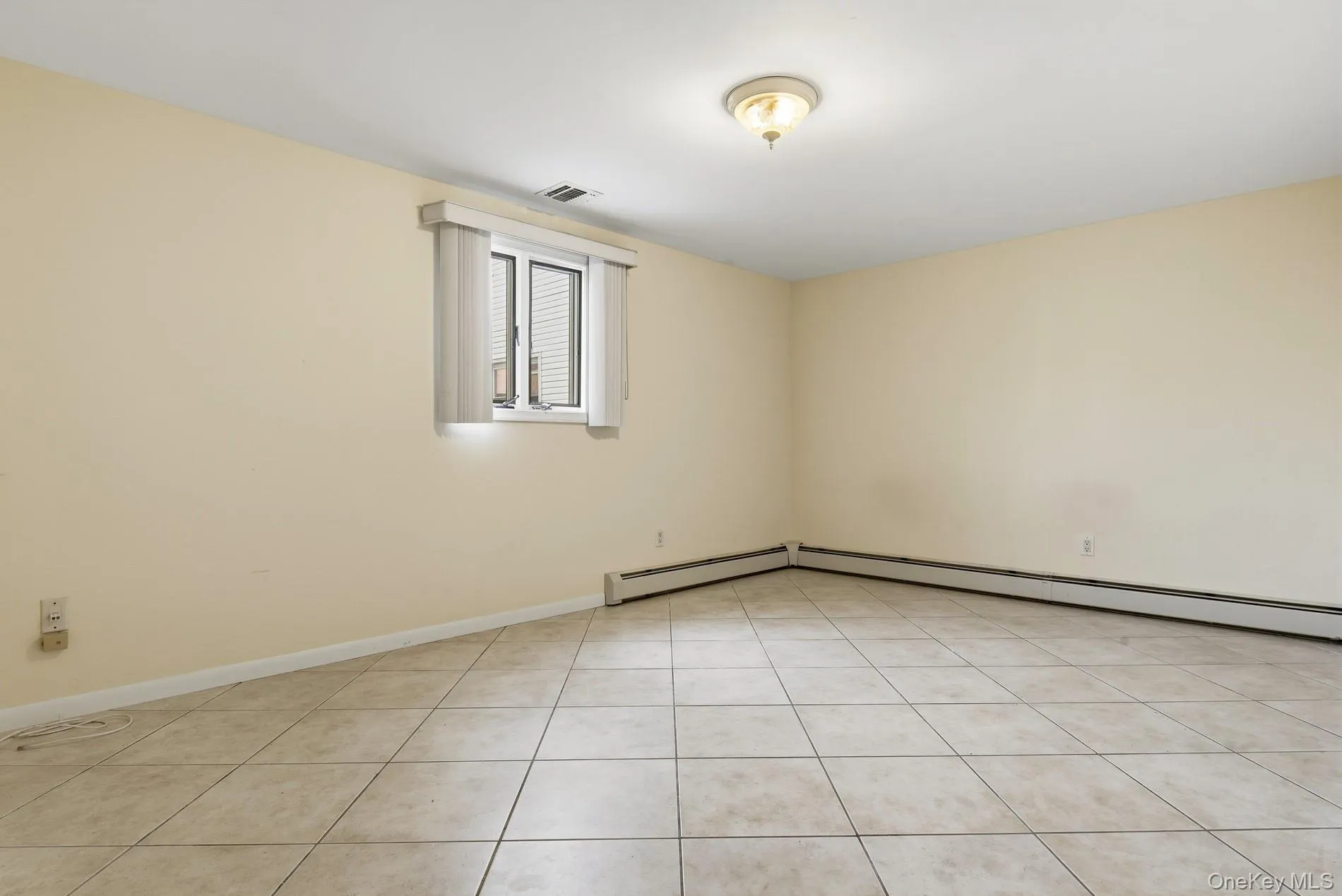 Unfurnished room featuring light tile patterned floors and baseboard heating Unfurnished room featuring light tile patterned floors and baseboard heating