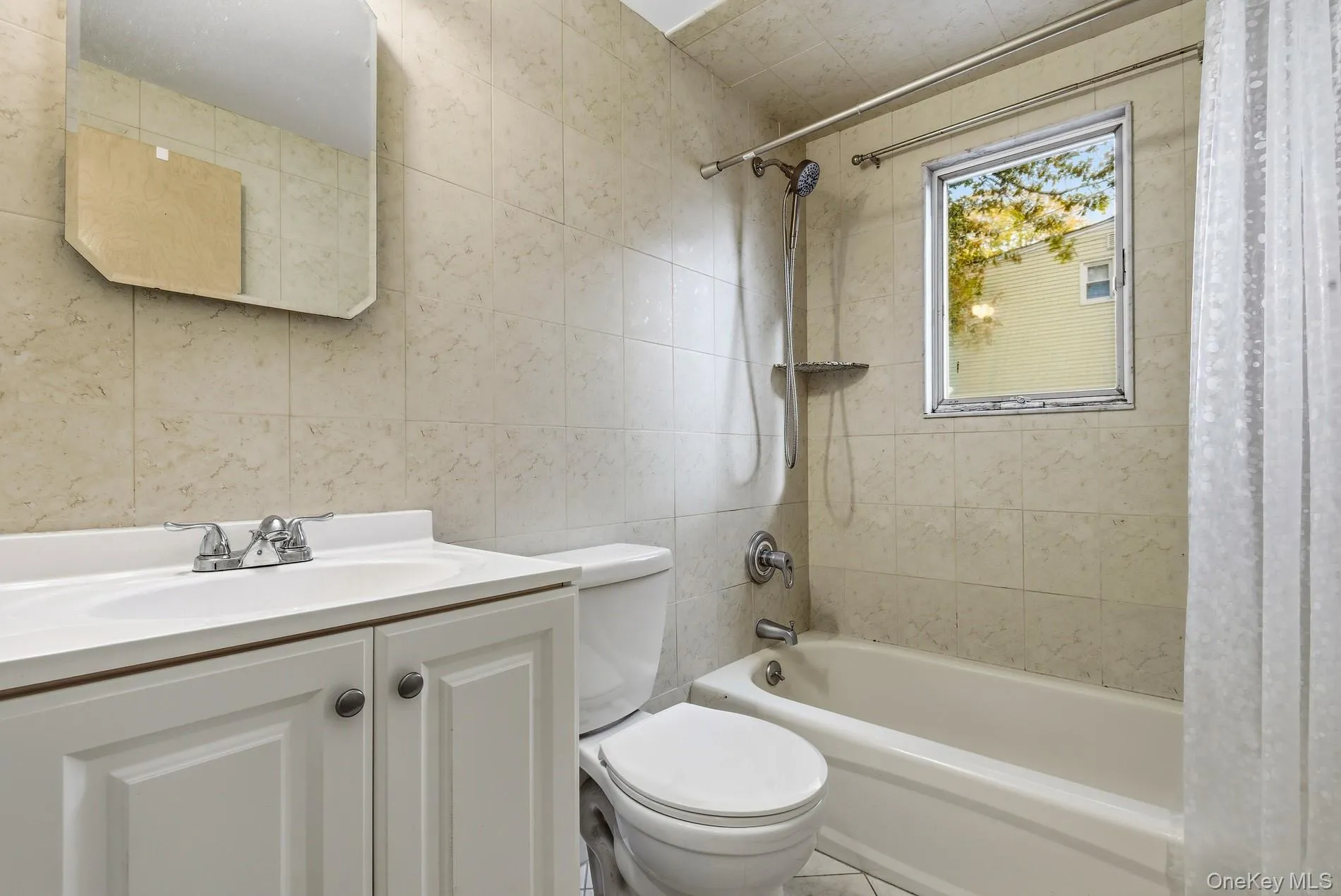 Bathroom with tile walls, shower / bath combo, and vanity Bathroom with tile walls, shower / bath combo, and vanity