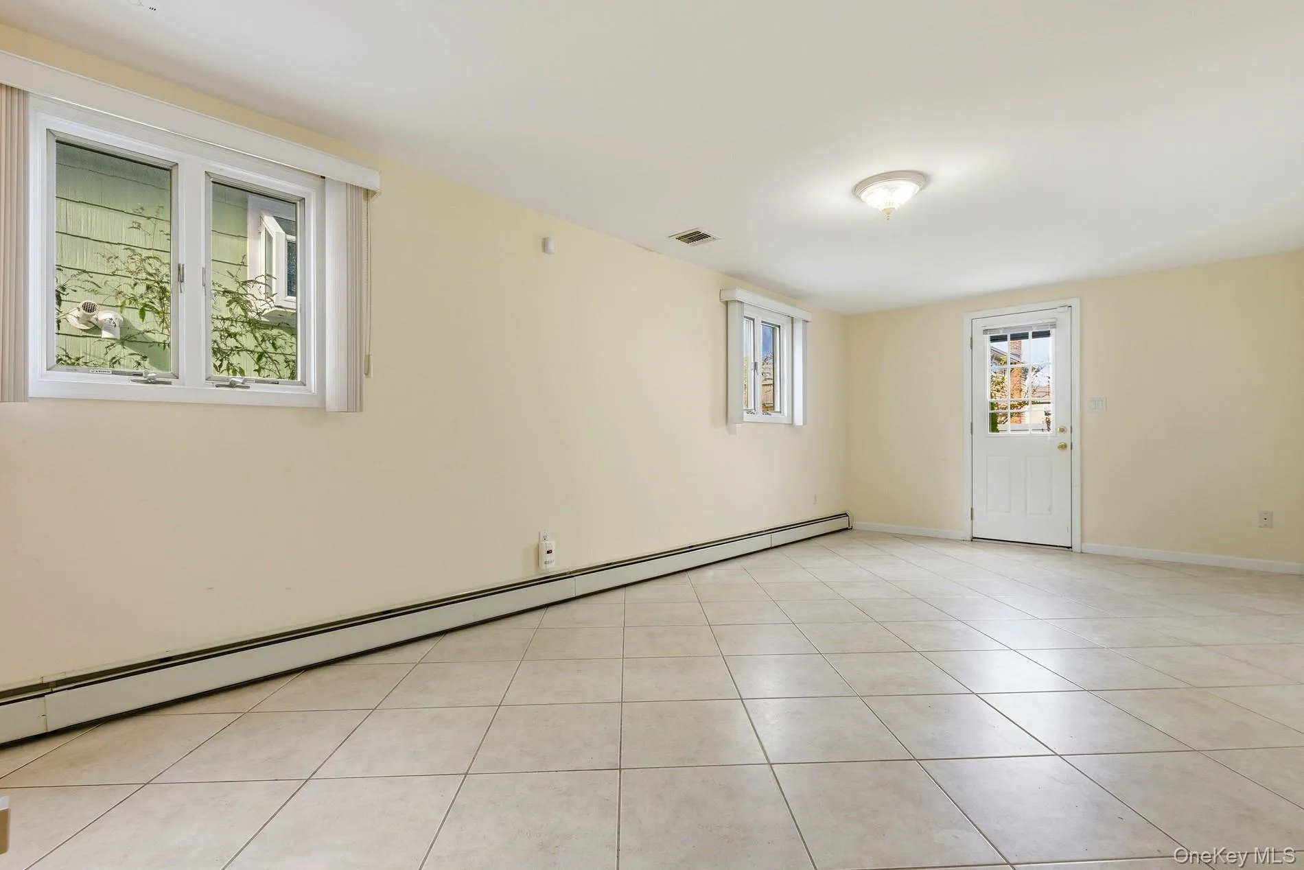 Empty room with baseboard heating and light tile patterned flooring Empty room with baseboard heating and light tile patterned flooring