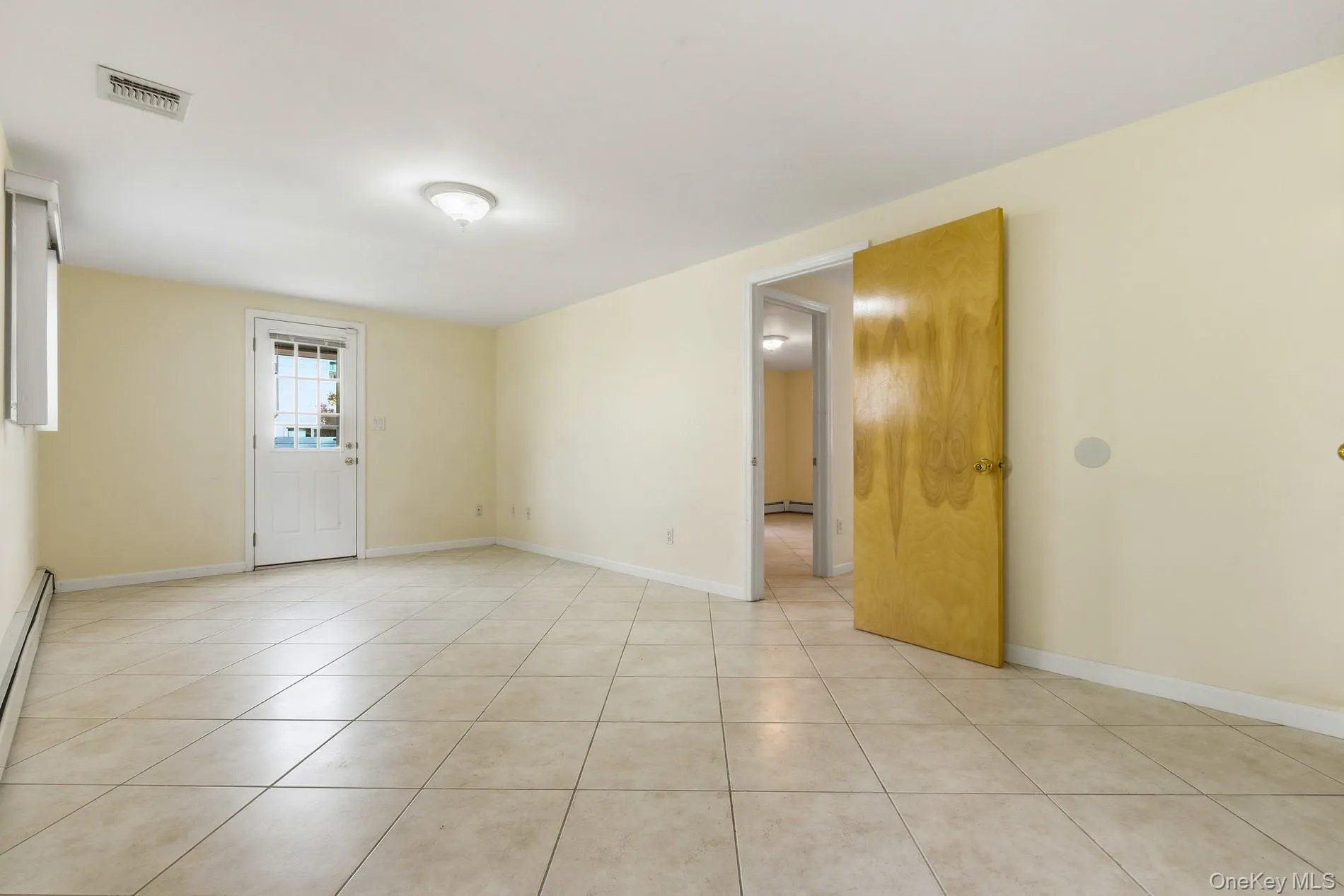 Spare room featuring light tile patterned floors and a baseboard heating unit Spare room featuring light tile patterned floors and a baseboard heating unit