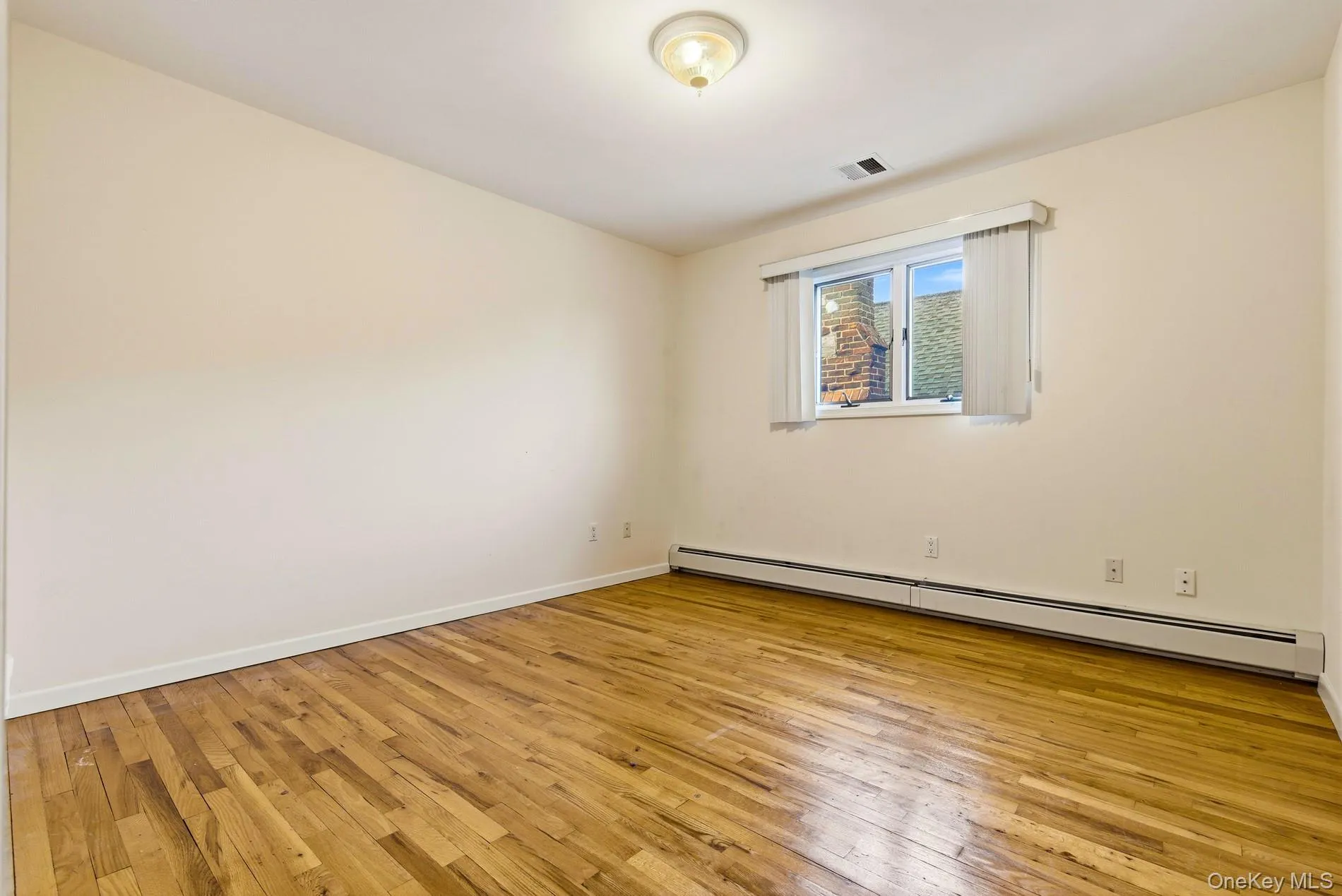 Unfurnished room featuring baseboard heating and light wood-style flooring Unfurnished room featuring baseboard heating and light wood-style flooring
