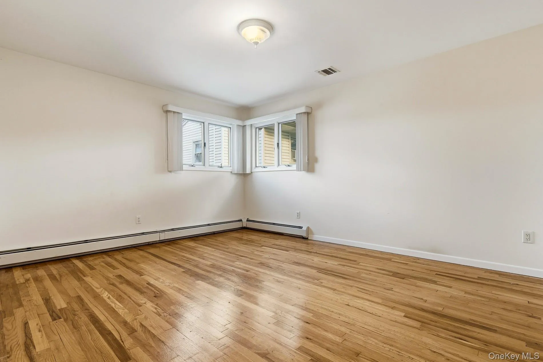 Unfurnished room featuring light wood-type flooring and a baseboard radiator Unfurnished room featuring light wood-type flooring and a baseboard radiator