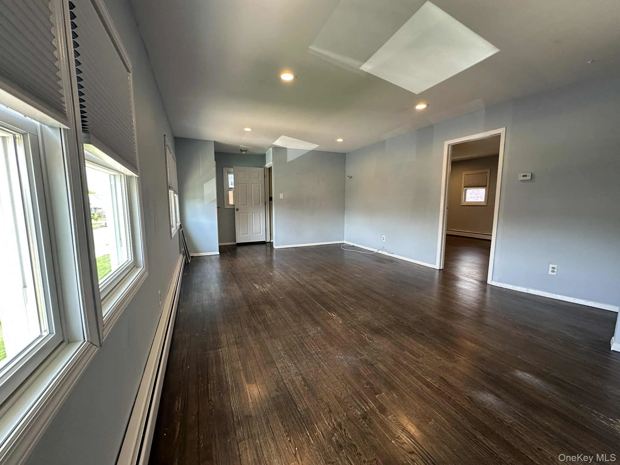 Empty room featuring recessed lighting, a baseboard radiator, dark wood finished floors, and a skylight Empty room featuring recessed lighting, a baseboard radiator, dark wood finished floors, and a skylight
