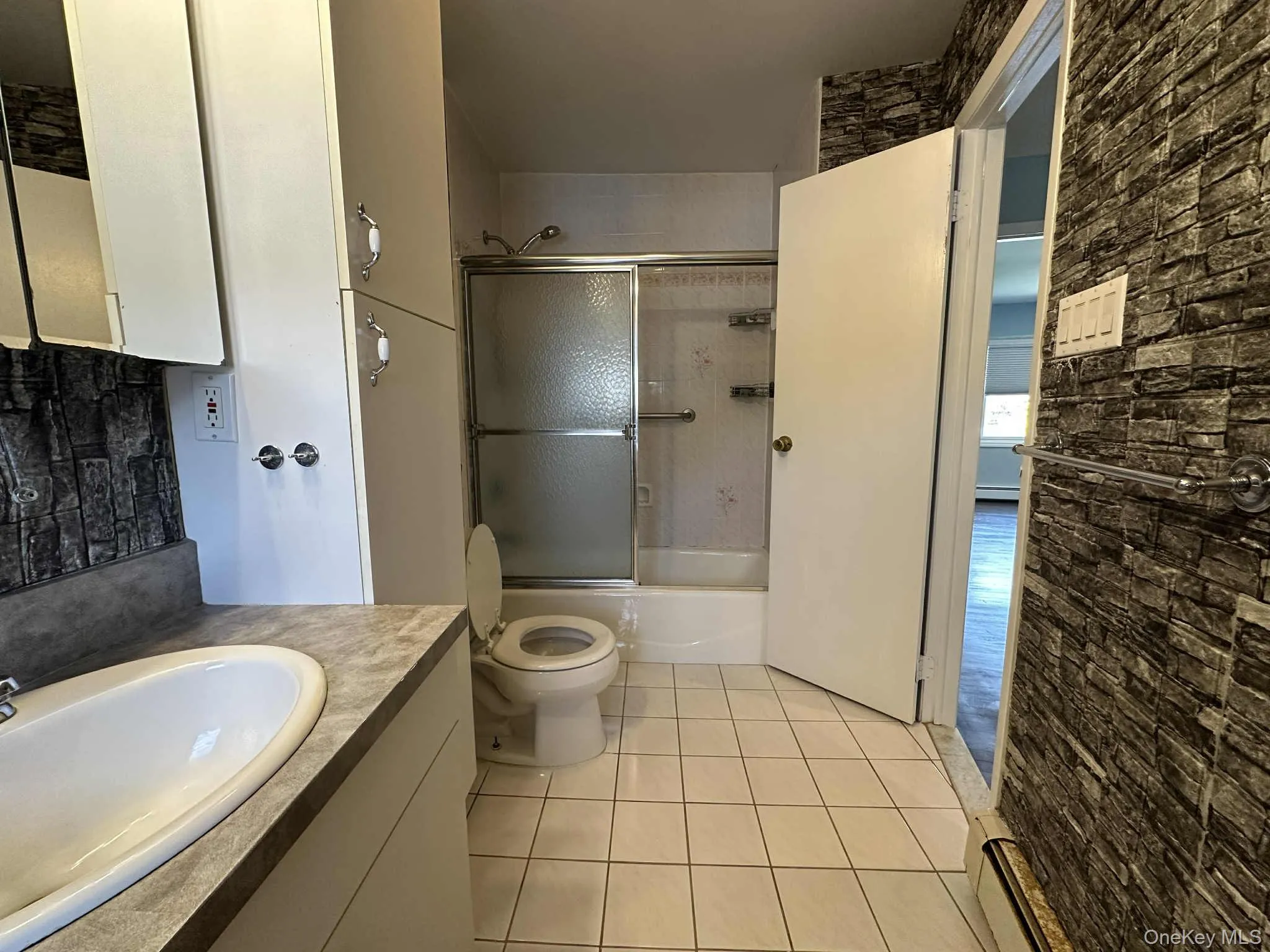 Full bathroom featuring vanity, light tile patterned flooring, and enclosed tub / shower combo Full bathroom featuring vanity, light tile patterned flooring, and enclosed tub / shower combo