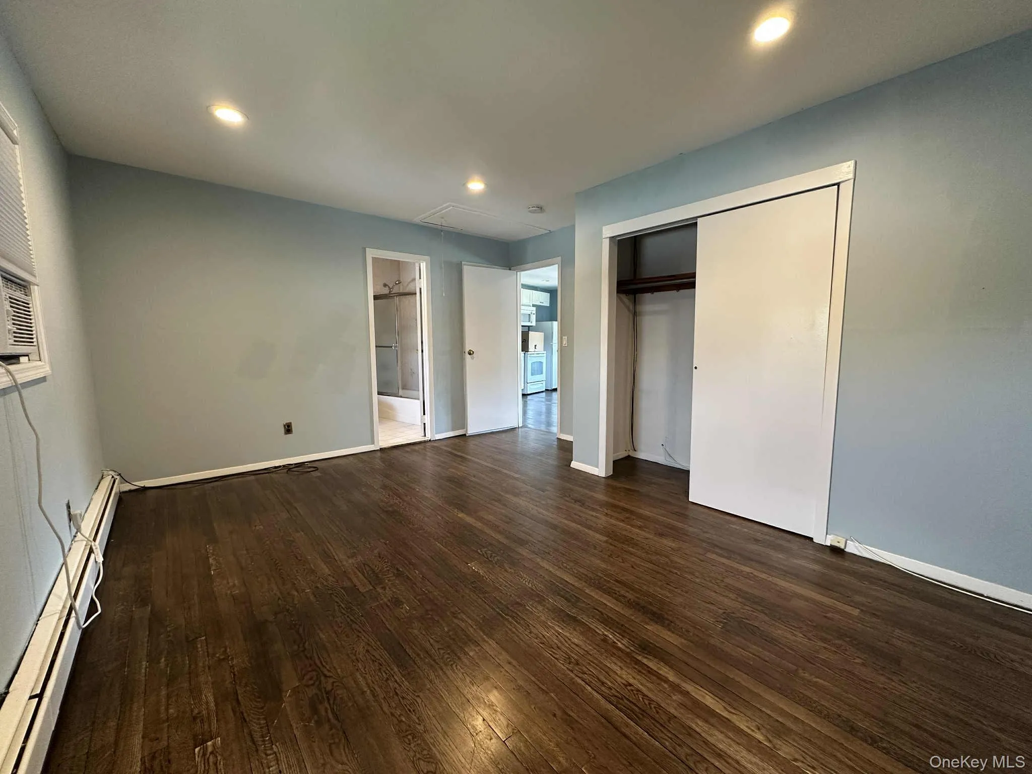 Unfurnished bedroom featuring a baseboard heating unit, recessed lighting, dark wood-style floors, and a closet Unfurnished bedroom featuring a baseboard heating unit, recessed lighting, dark wood-style floors, and a closet
