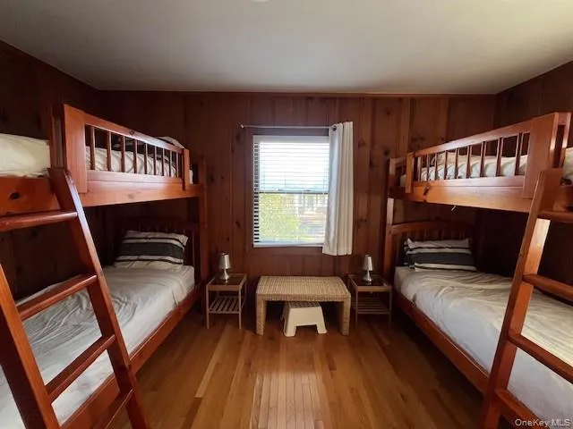 Bedroom featuring wood walls and wood-type flooring Bedroom featuring wood walls and wood-type flooring