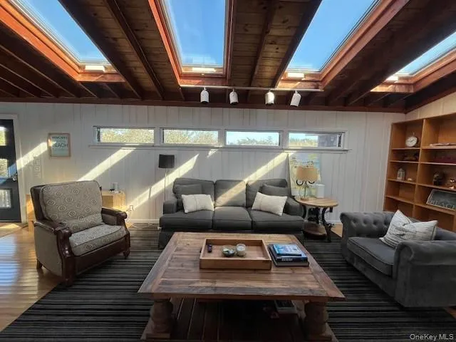 Living area with beamed ceiling, wood finished floors, and a skylight Living area with beamed ceiling, wood finished floors, and a skylight