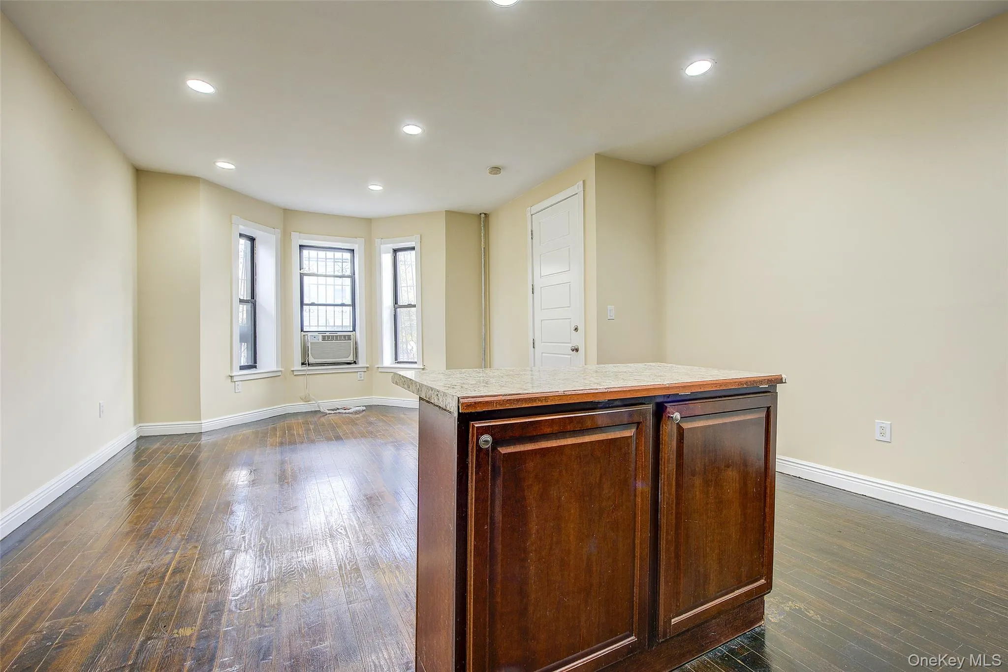 Kitchen with recessed lighting, dark wood-type flooring, light countertops, and a kitchen island Kitchen with recessed lighting, dark wood-type flooring, light countertops, and a kitchen island