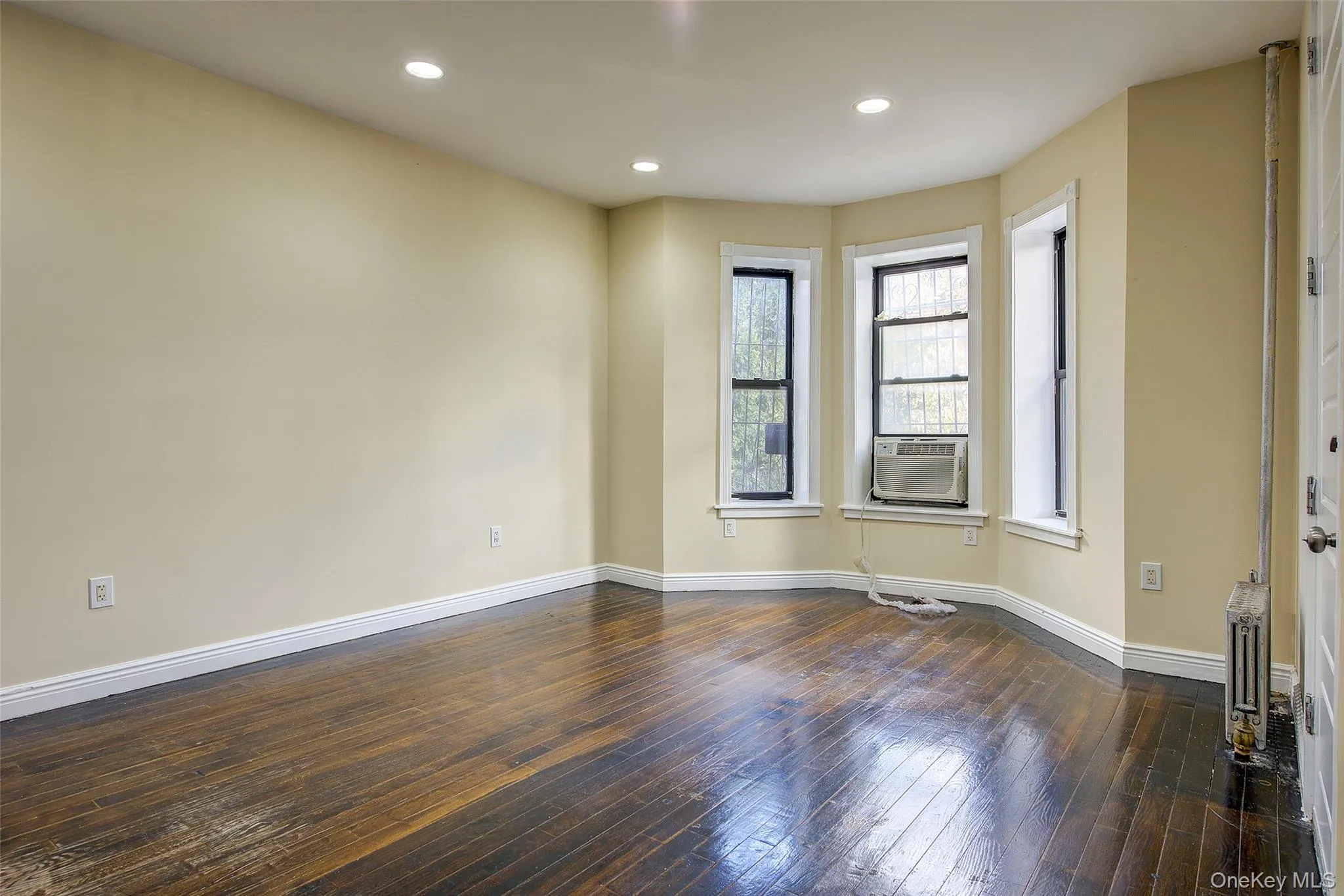 Empty room with recessed lighting, dark wood finished floors, and radiator Empty room with recessed lighting, dark wood finished floors, and radiator
