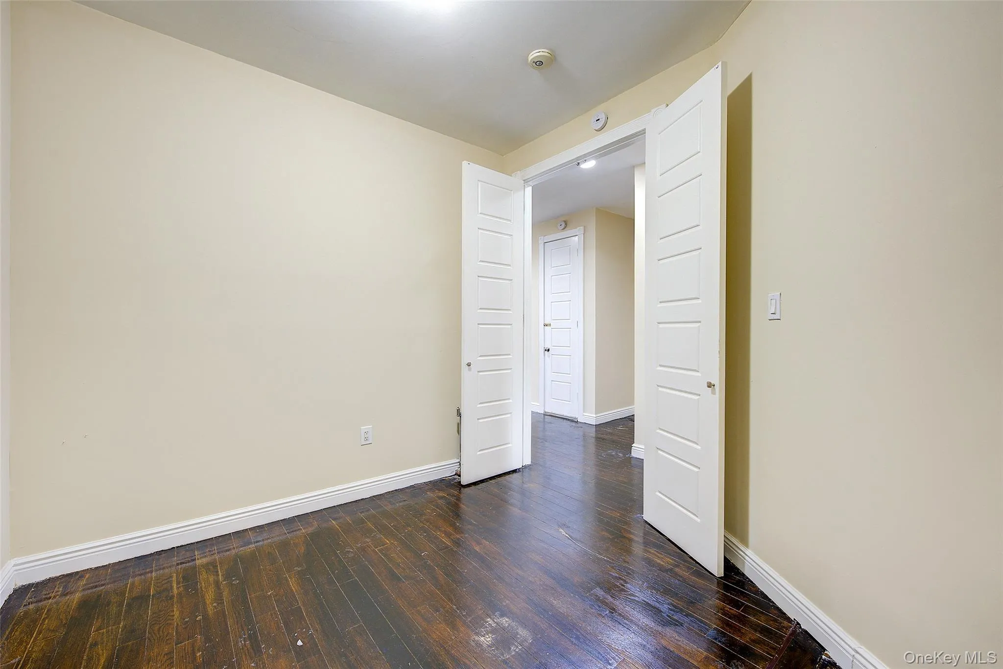Empty room with baseboards and dark wood-style flooring Empty room with baseboards and dark wood-style flooring