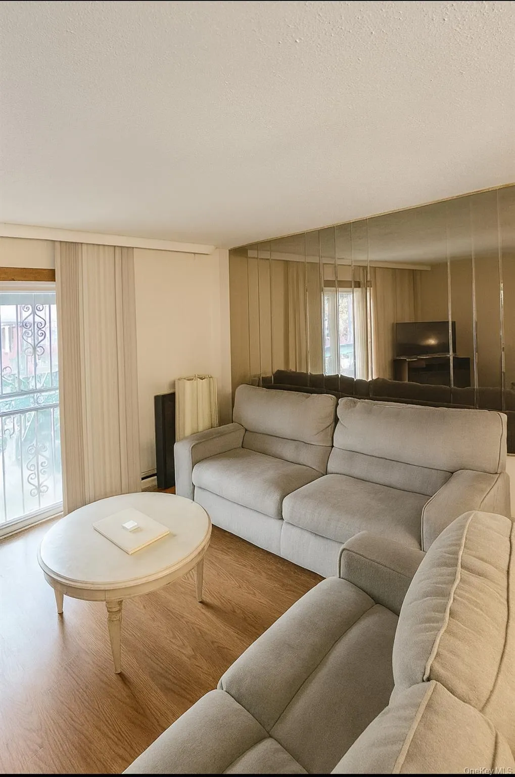 Living area with plenty of natural light, wood finished floors, a textured ceiling, and radiator heating unit Living area with plenty of natural light, wood finished floors, a textured ceiling, and radiator heating unit