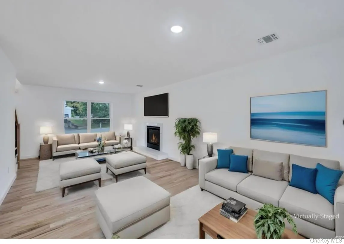 Living area featuring light wood-style flooring, recessed lighting, and a glass covered fireplace Living area featuring light wood-style flooring, recessed lighting, and a glass covered fireplace