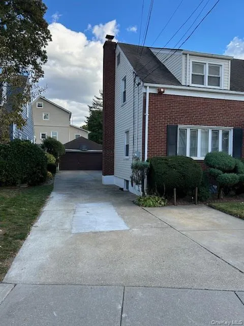 View of side of home with an outdoor structure, brick siding, and a detached garage View of side of home with an outdoor structure, brick siding, and a detached garage