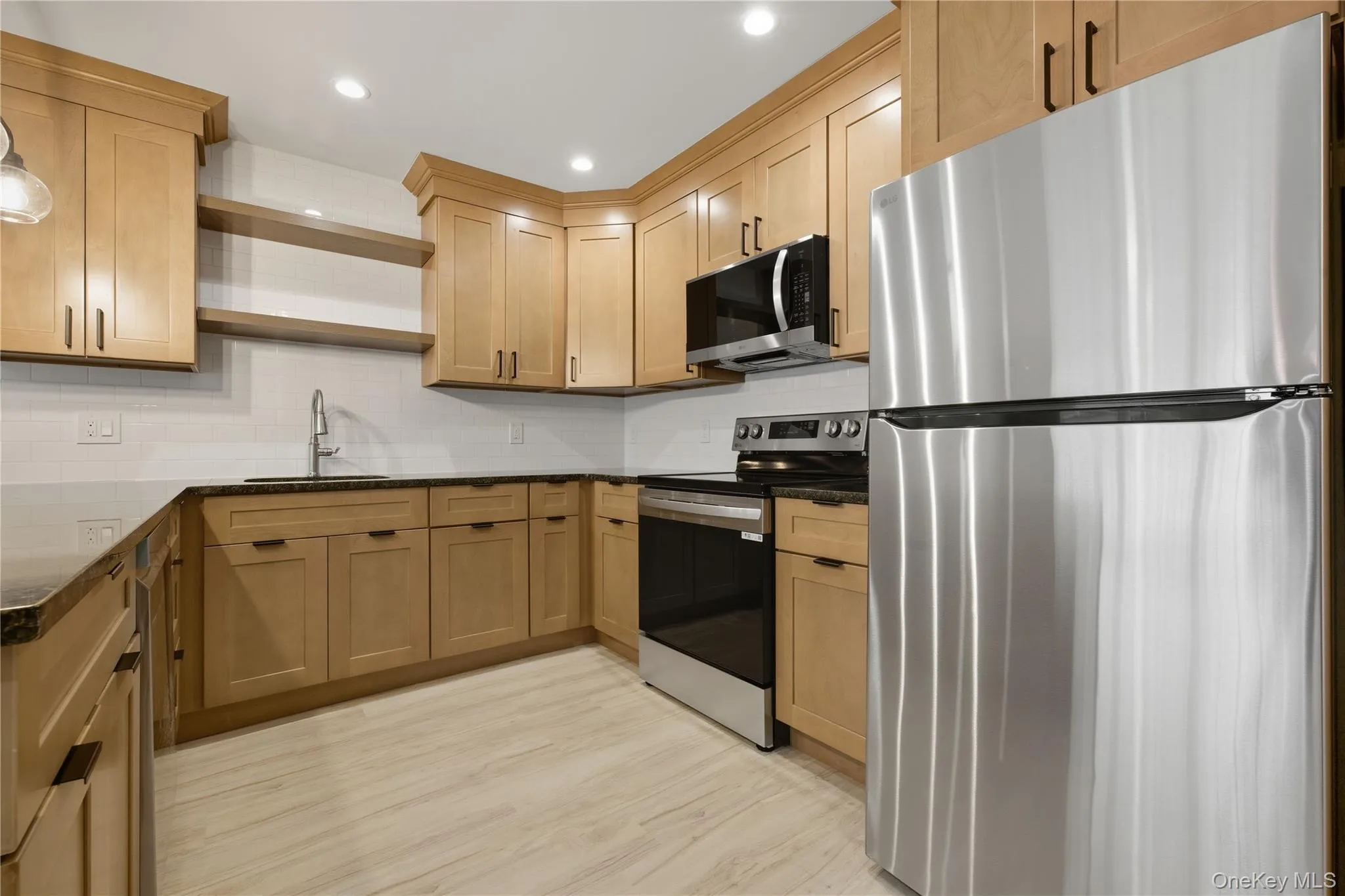 Kitchen with appliances with stainless steel finishes, granite countertops, open shelves, backsplash, and recessed lighting Kitchen with appliances with stainless steel finishes, granite countertops, open shelves, backsplash, and recessed lighting