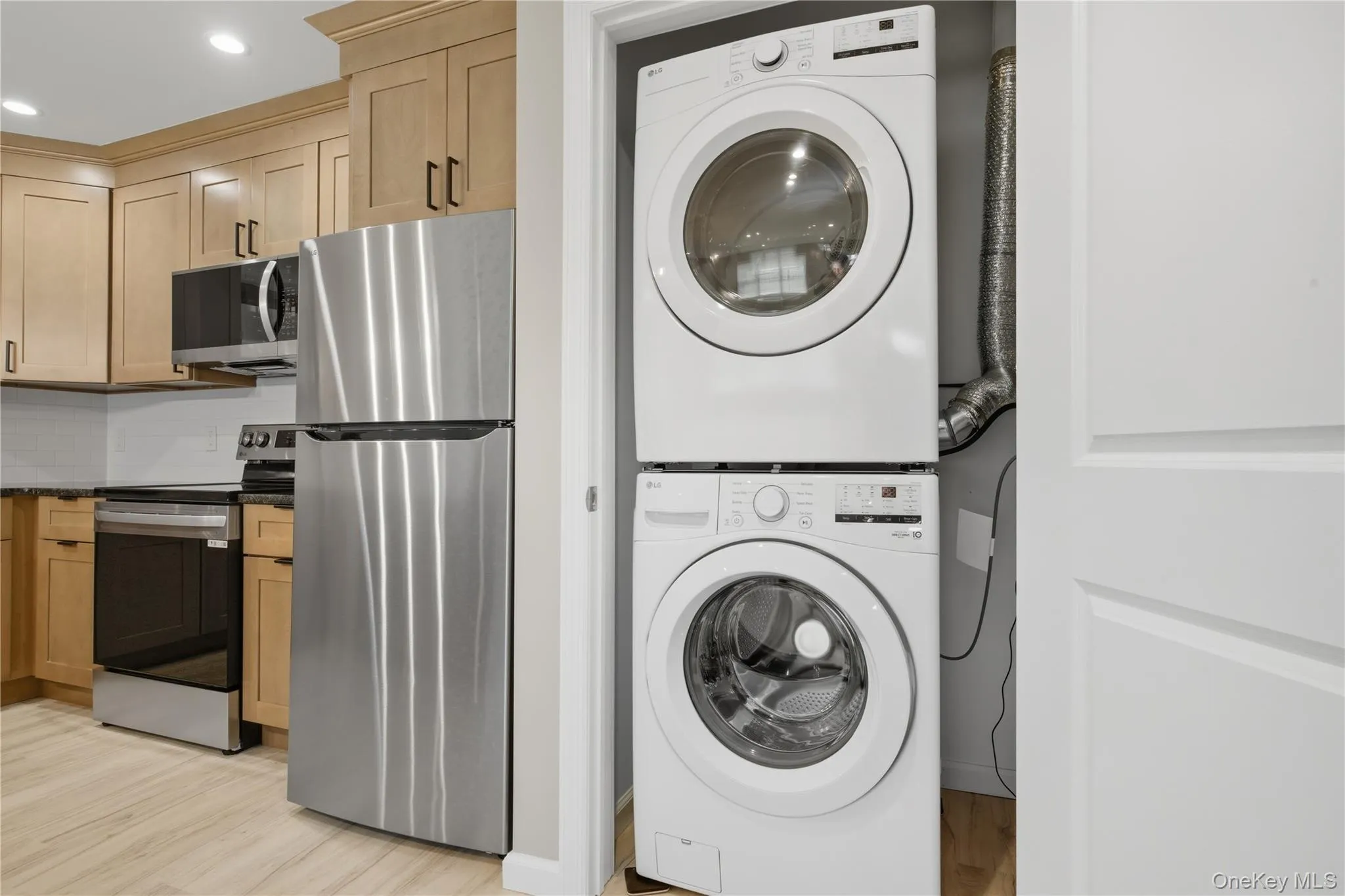 Laundry room with Stacked Washer / drying machine, luxury vinyl flooring, and recessed lighting Laundry room with Stacked Washer / drying machine, luxury vinyl flooring, and recessed lighting