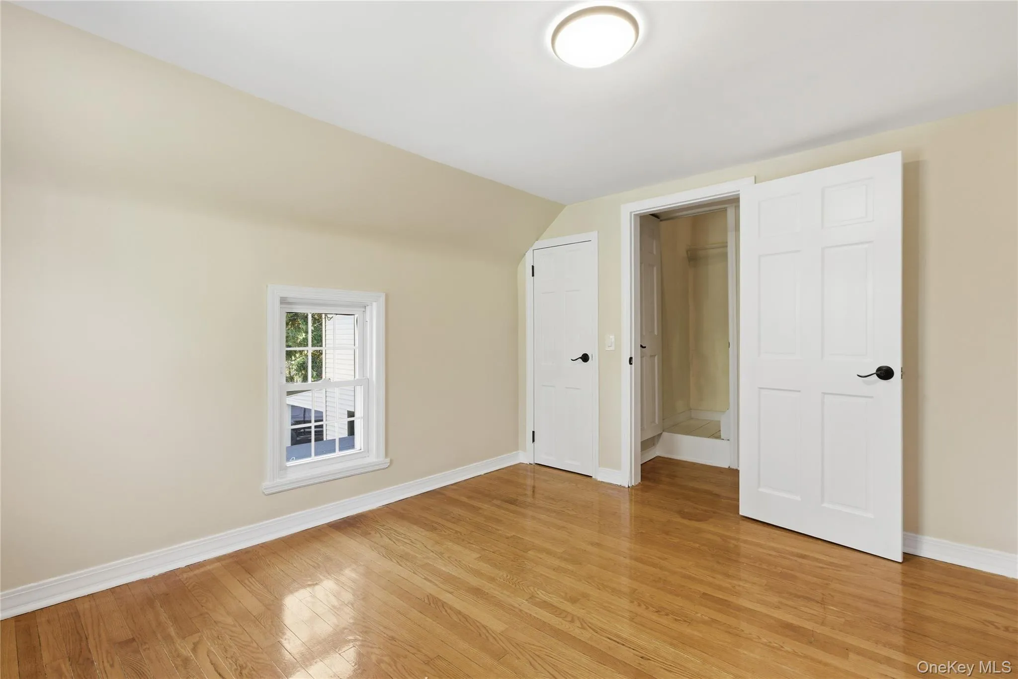 Unfurnished bedroom with light wood finished floors and lofted ceiling Unfurnished bedroom with light wood finished floors and lofted ceiling