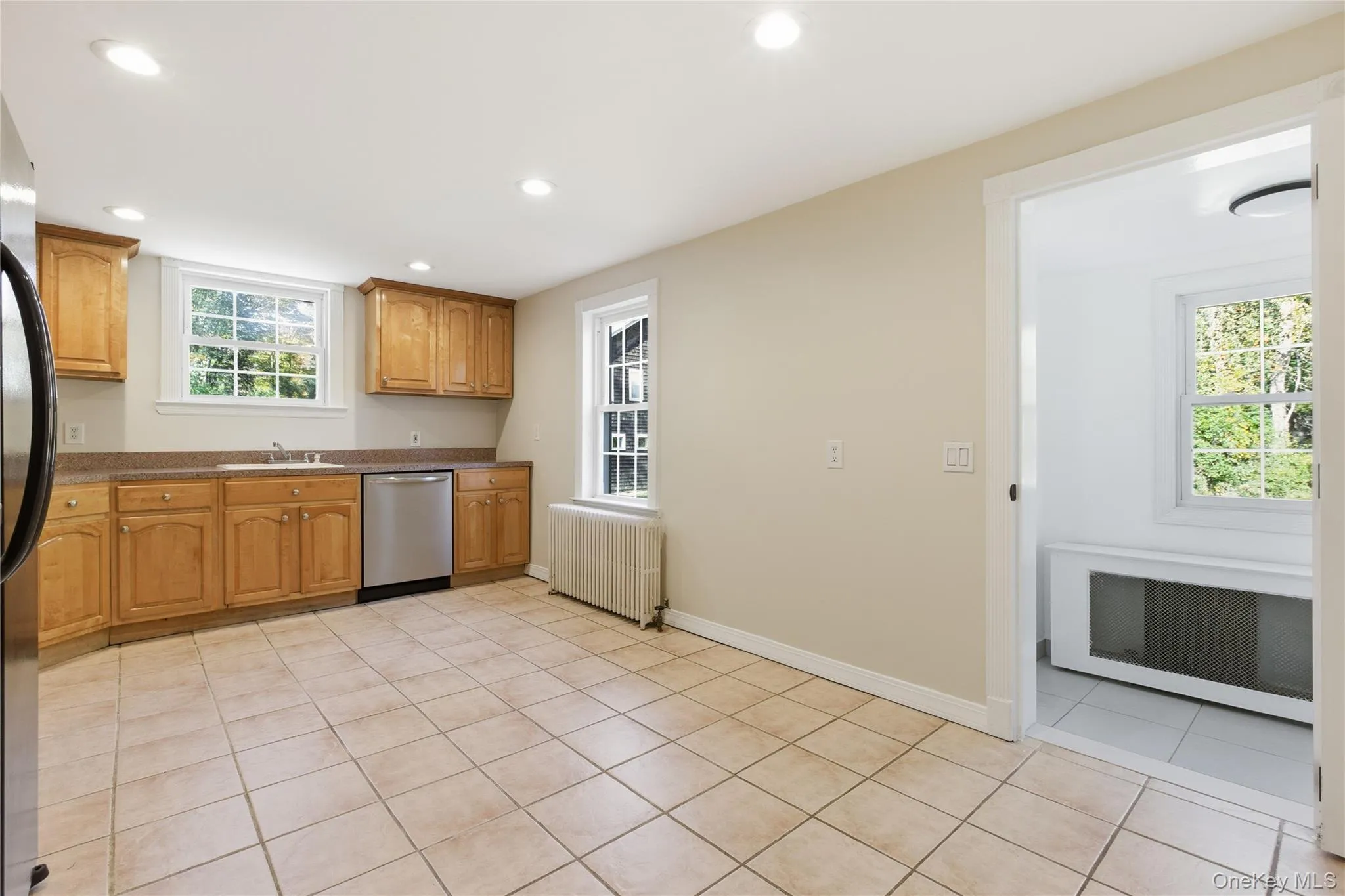 Kitchen featuring light tile patterned floors, radiator, appliances with stainless steel finishes, recessed lighting, and dark stone countertops Kitchen featuring light tile patterned floors, radiator, appliances with stainless steel finishes, recessed lighting, and dark stone countertops