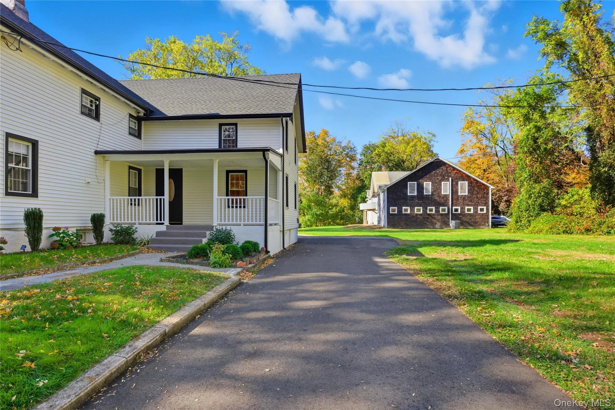 View of property exterior with covered porch, a lawn, and roof with shingles View of property exterior with covered porch, a lawn, and roof with shingles