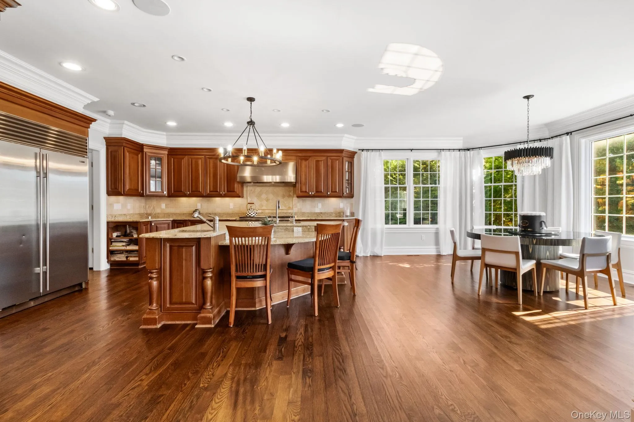 Kitchen featuring a chandelier, brown cabinetry, pendant lighting, crown molding, and recessed lighting Kitchen featuring a chandelier, brown cabinetry, pendant lighting, crown molding, and recessed lighting