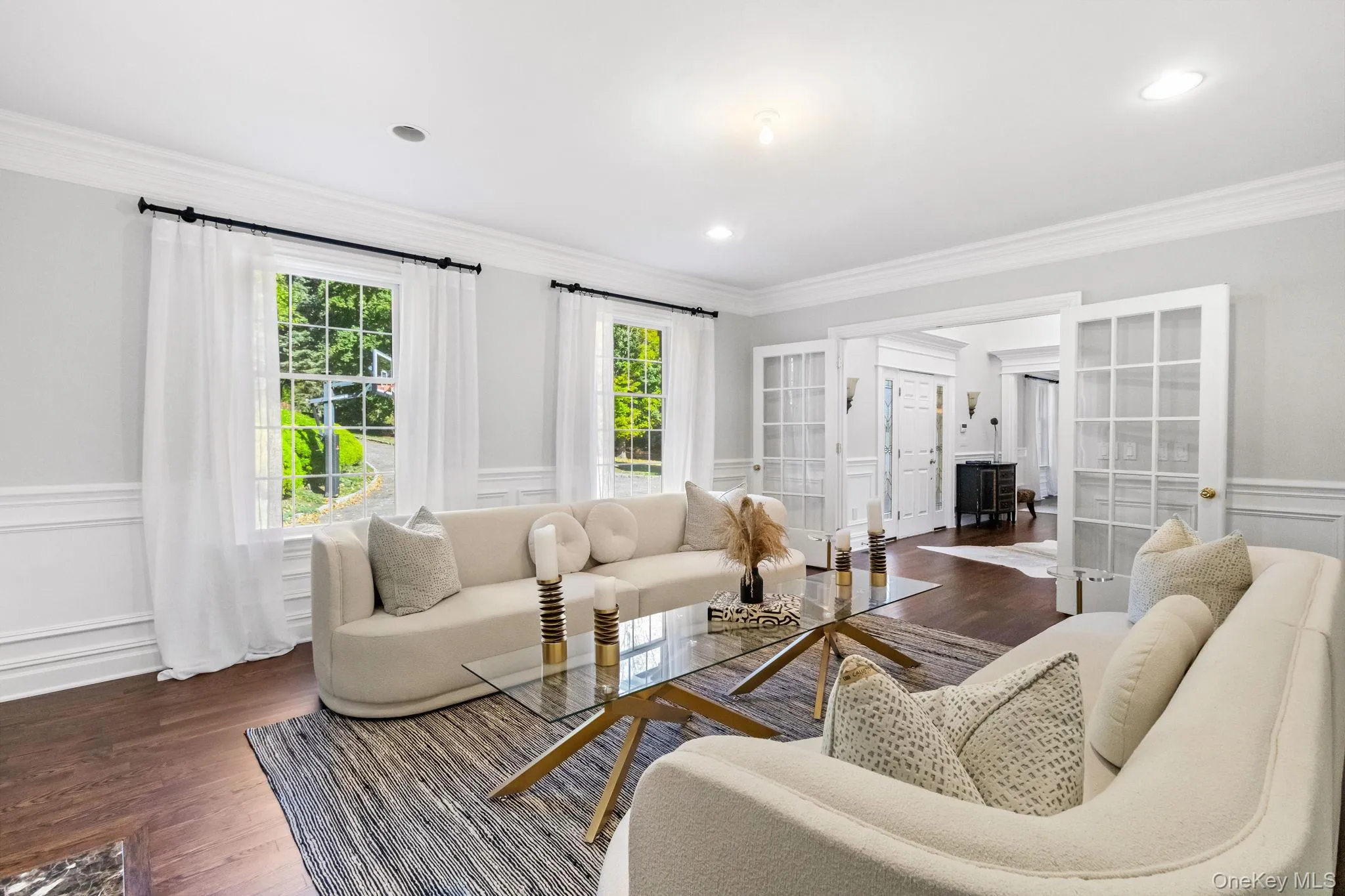 Living room featuring a decorative wall, wainscoting, french doors, ornamental molding, and dark wood-type flooring Living room featuring a decorative wall, wainscoting, french doors, ornamental molding, and dark wood-type flooring