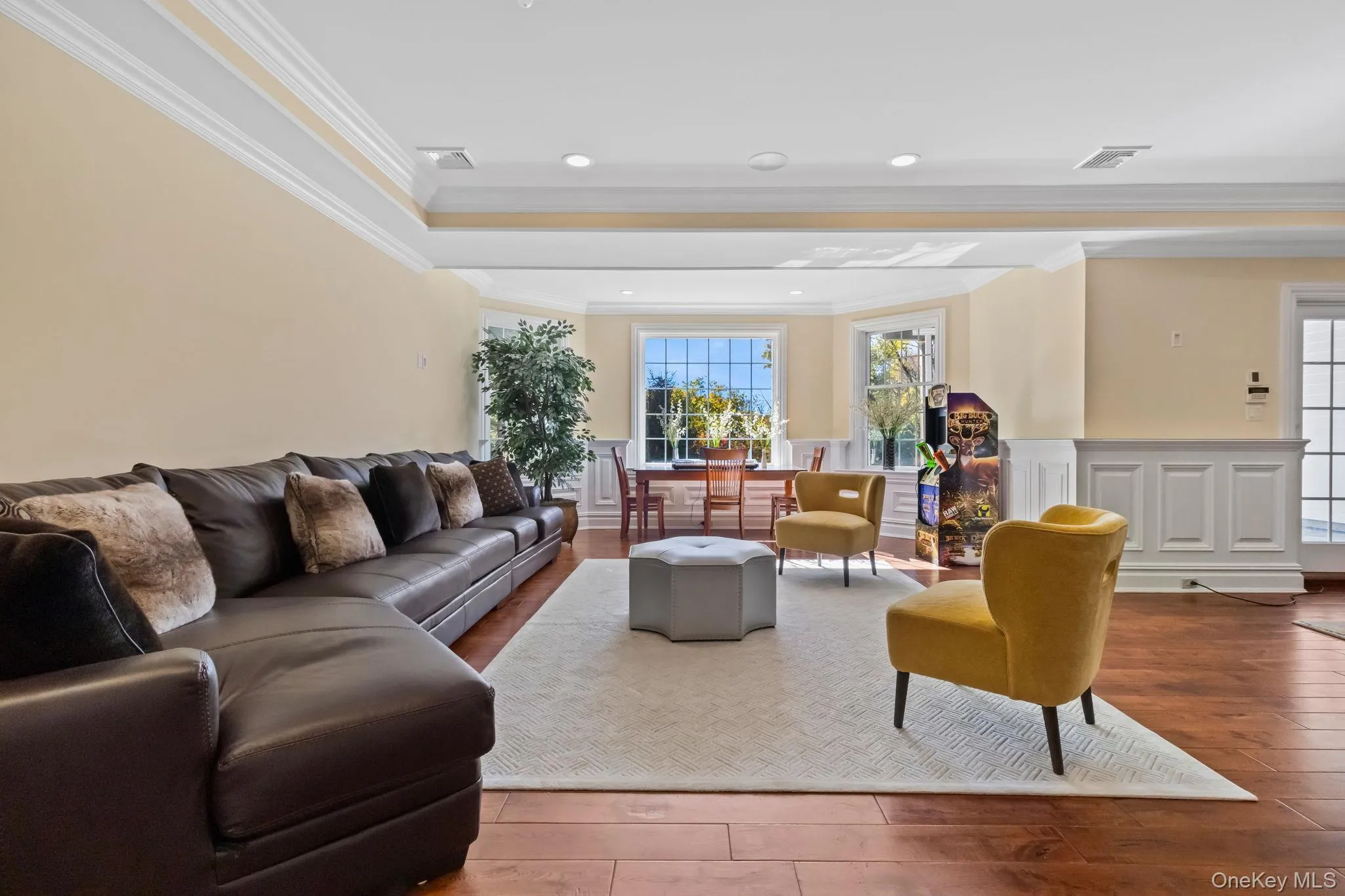 Living area with hardwood / wood-style flooring, crown molding, a raised ceiling, a wainscoted wall, and recessed lighting Living area with hardwood / wood-style flooring, crown molding, a raised ceiling, a wainscoted wall, and recessed lighting