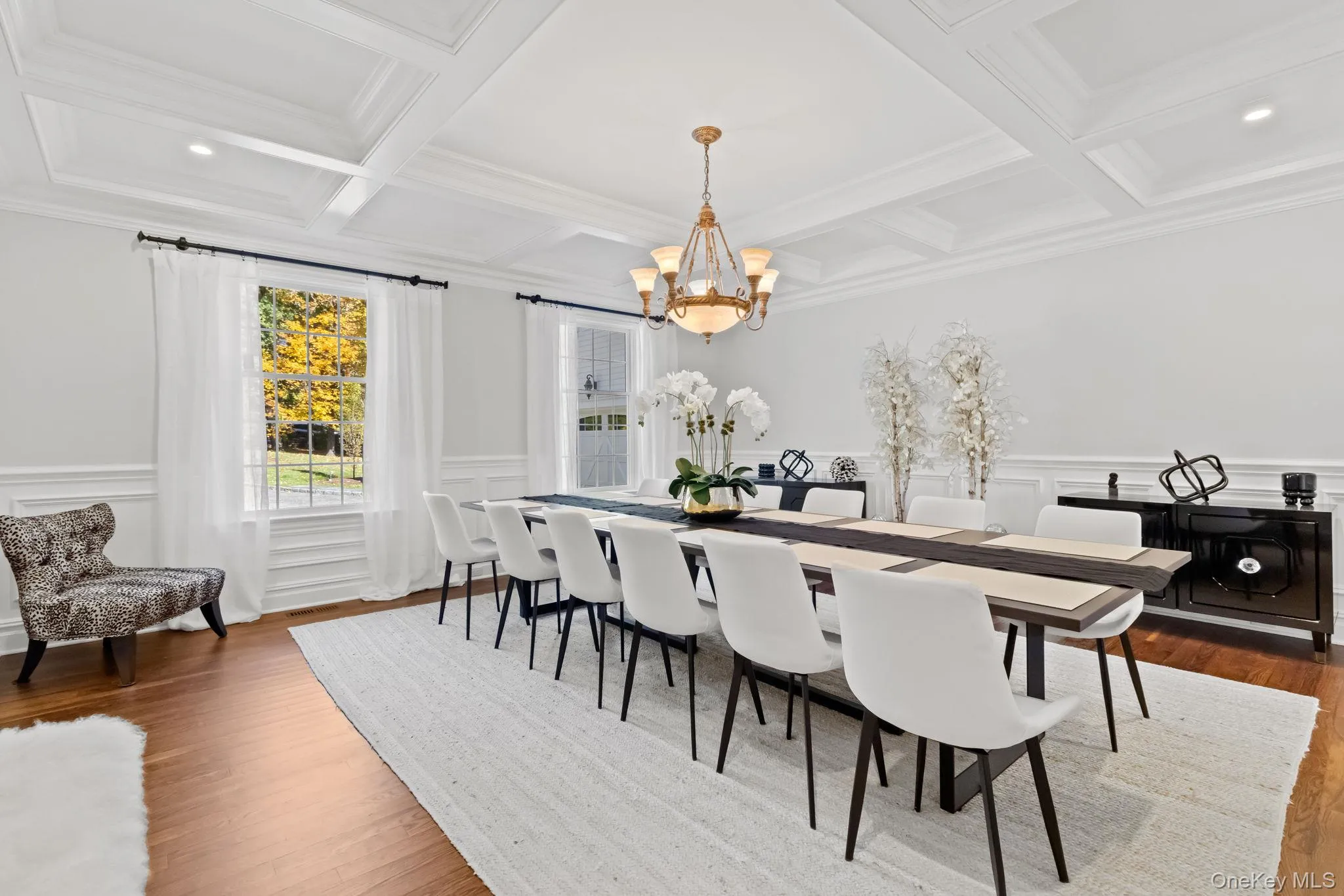 Dining space featuring a decorative wall, beam ceiling, a wainscoted wall, a chandelier, and wood finished floors Dining space featuring a decorative wall, beam ceiling, a wainscoted wall, a chandelier, and wood finished floors