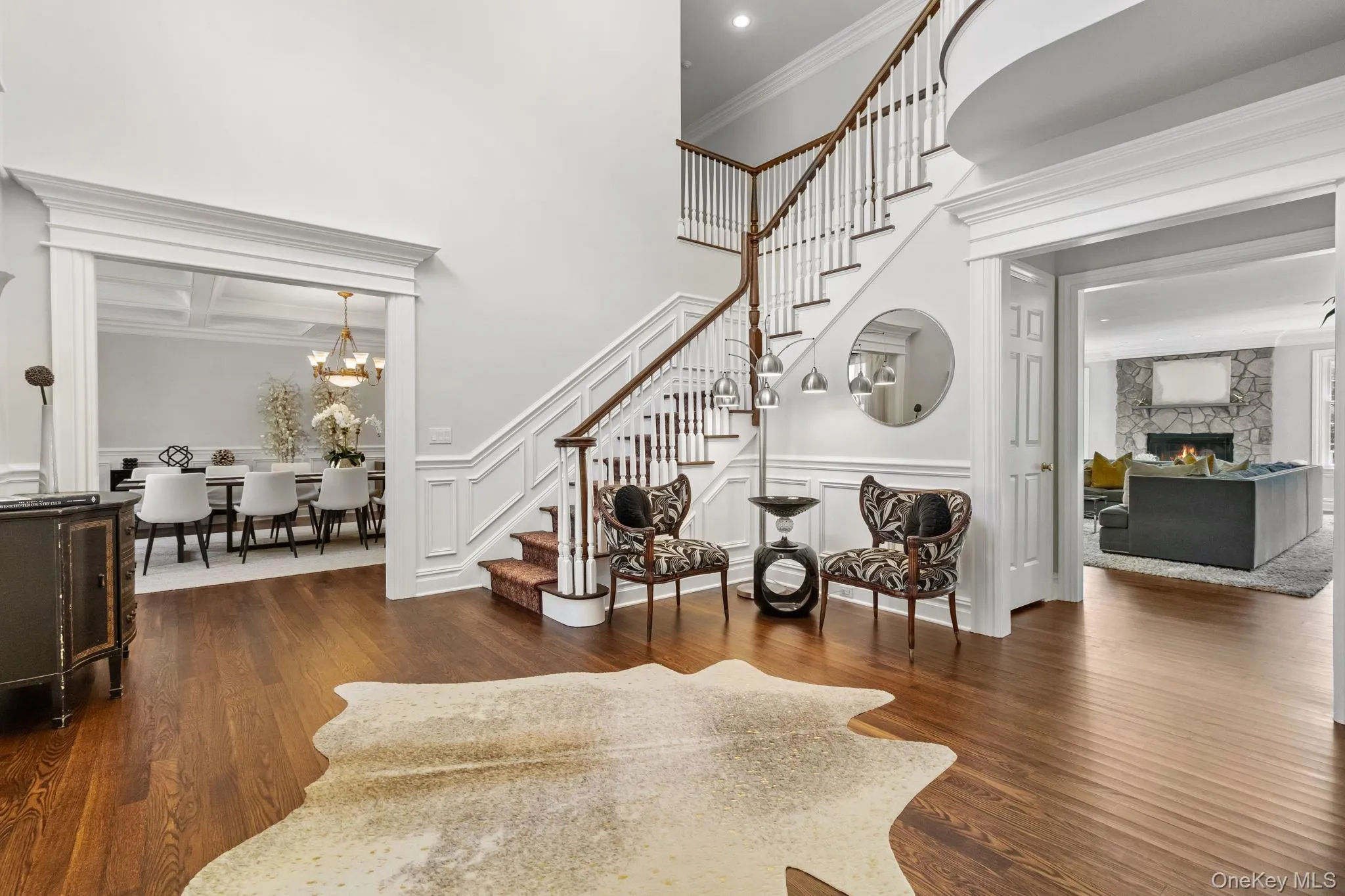 Entryway featuring stairway, dark wood-type flooring, a stone fireplace, ornamental molding, and a chandelier Entryway featuring stairway, dark wood-type flooring, a stone fireplace, ornamental molding, and a chandelier