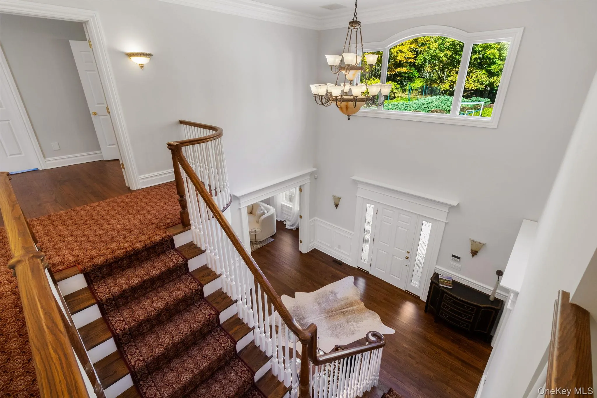 Foyer featuring stairway, dark wood finished floors, a chandelier, and crown molding Foyer featuring stairway, dark wood finished floors, a chandelier, and crown molding