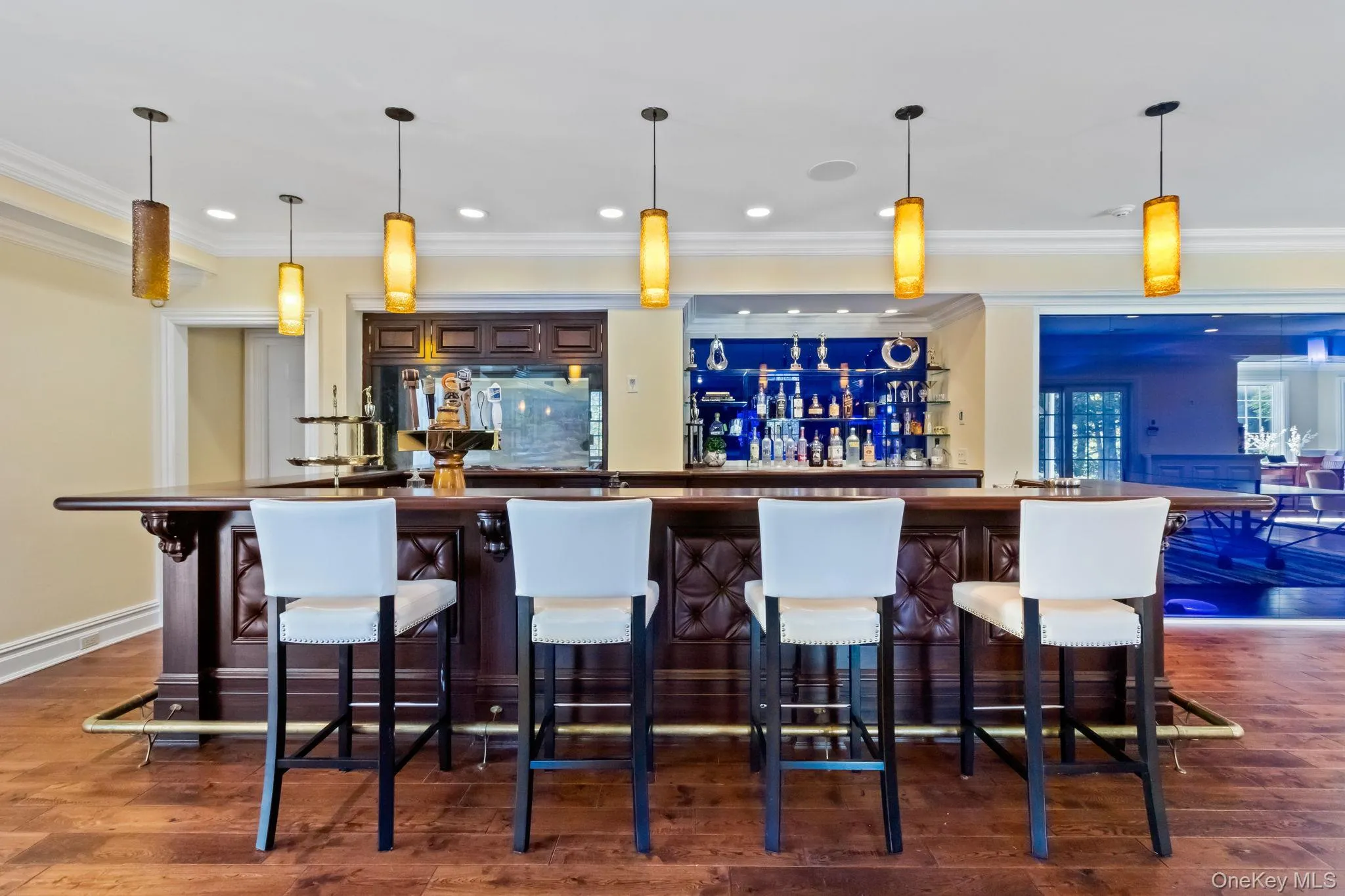 Community bar area with pendant lighting, dark brown cabinets, crown molding, and dark countertops Community bar area with pendant lighting, dark brown cabinets, crown molding, and dark countertops
