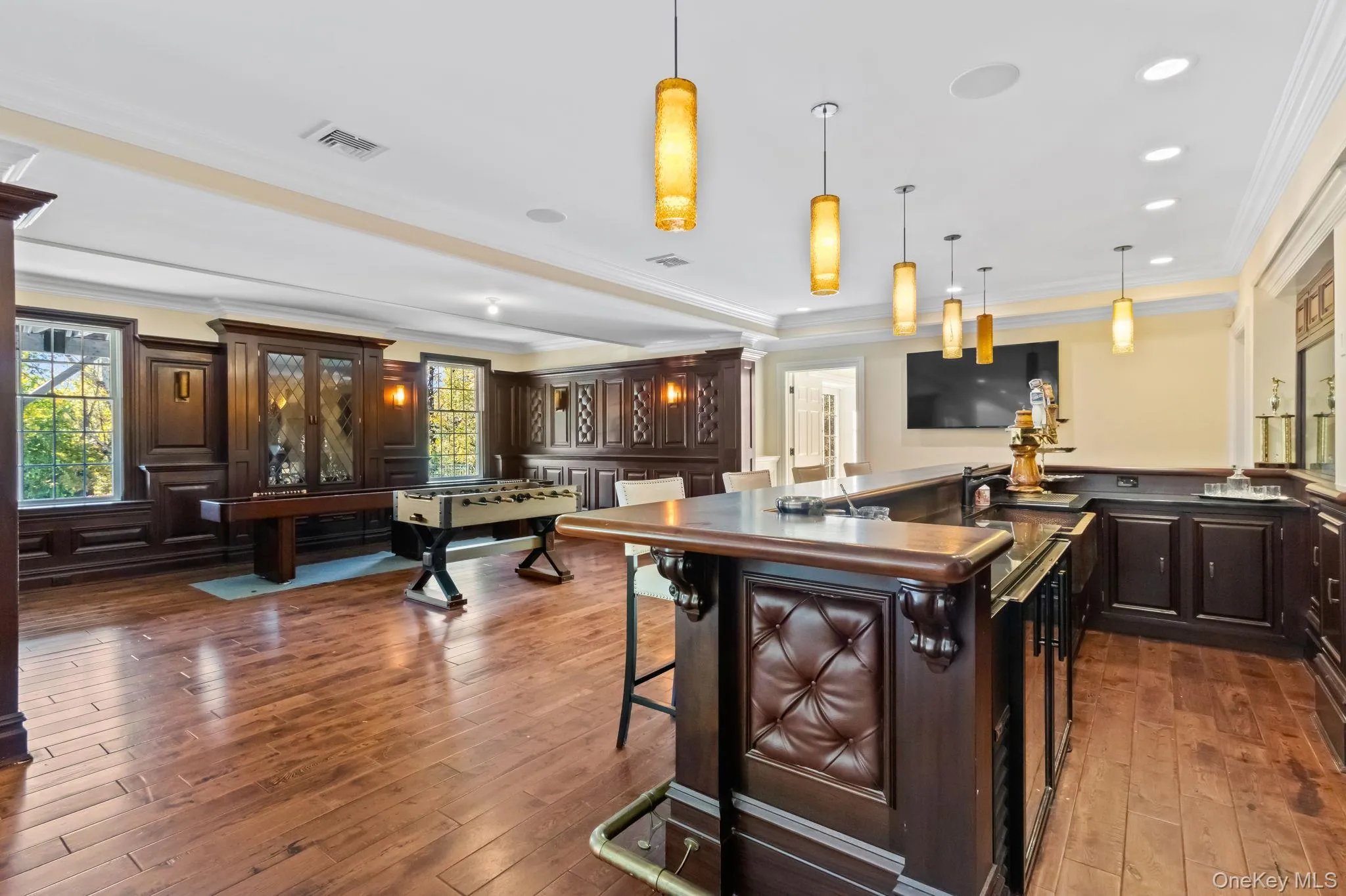 Kitchen featuring dark countertops, crown molding, a kitchen breakfast bar, decorative light fixtures, and dark brown cabinets Kitchen featuring dark countertops, crown molding, a kitchen breakfast bar, decorative light fixtures, and dark brown cabinets