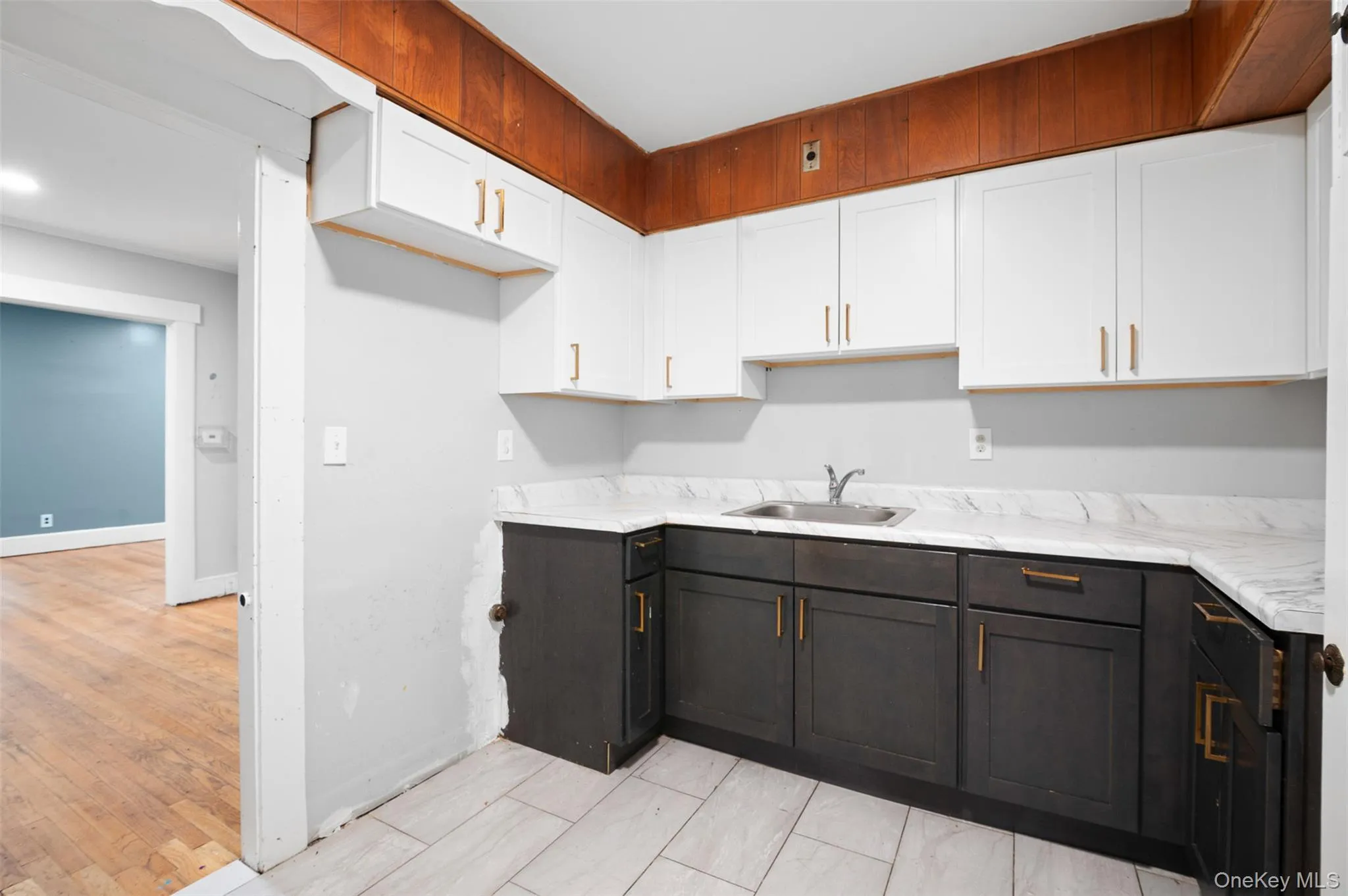 Kitchen featuring white cabinets, light wood-style flooring, and dark brown cabinetry Kitchen featuring white cabinets, light wood-style flooring, and dark brown cabinetry