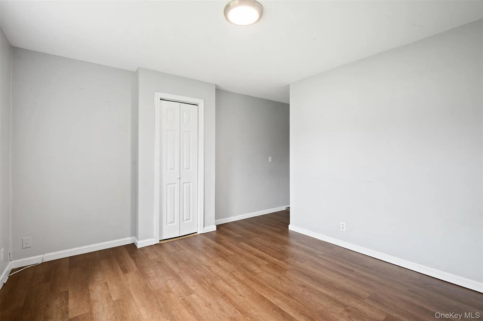 Unfurnished bedroom featuring wood finished floors and a closet Unfurnished bedroom featuring wood finished floors and a closet