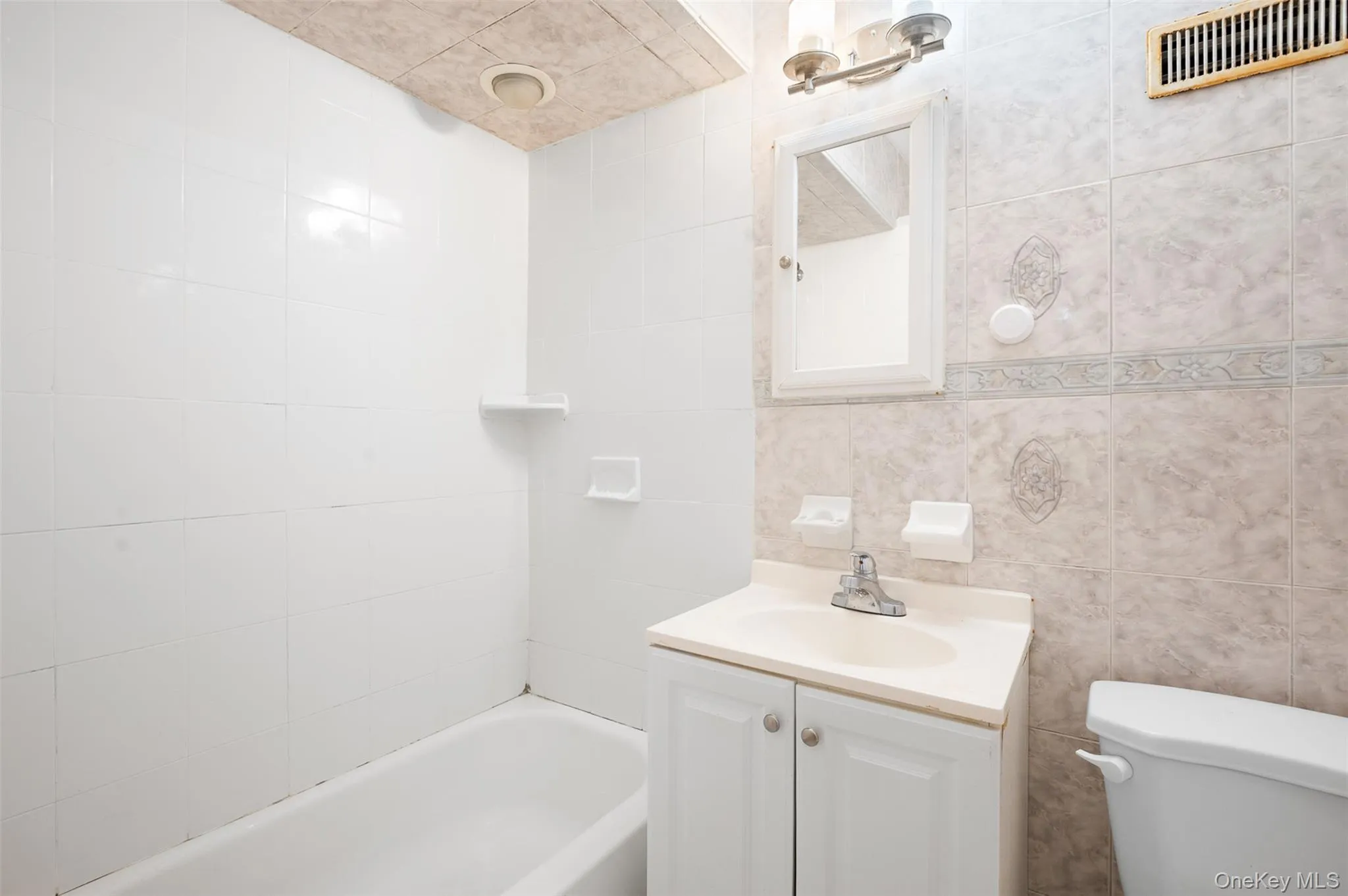 Full bath featuring vanity, tile walls, and bathtub / shower combination Full bath featuring vanity, tile walls, and bathtub / shower combination