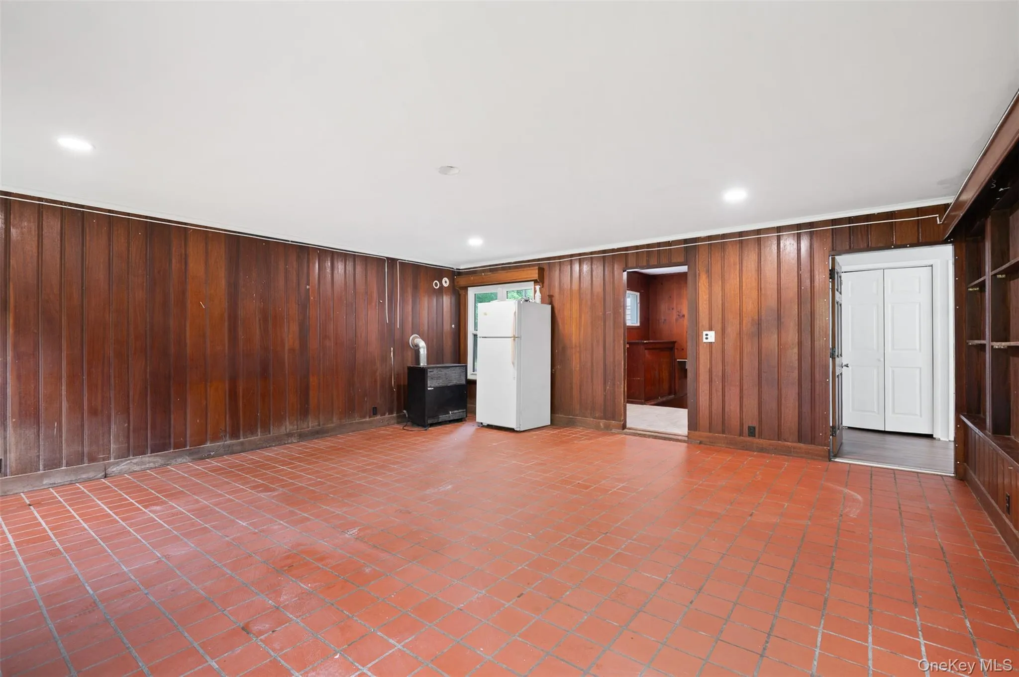 Unfurnished living room featuring recessed lighting, tile patterned floors, and wood walls Unfurnished living room featuring recessed lighting, tile patterned floors, and wood walls