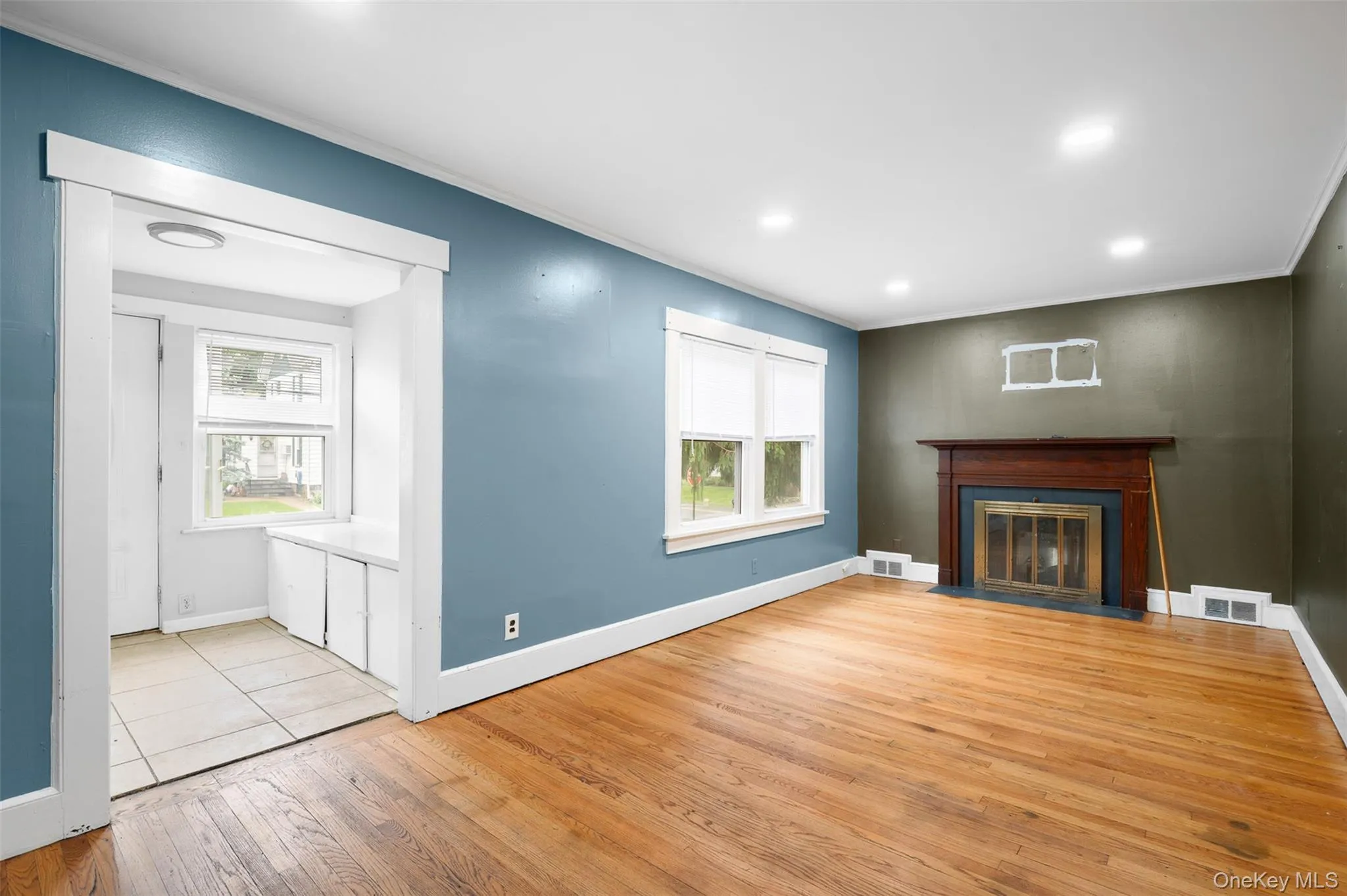 Unfurnished living room with light wood finished floors, ornamental molding, a fireplace with flush hearth, and recessed lighting Unfurnished living room with light wood finished floors, ornamental molding, a fireplace with flush hearth, and recessed lighting
